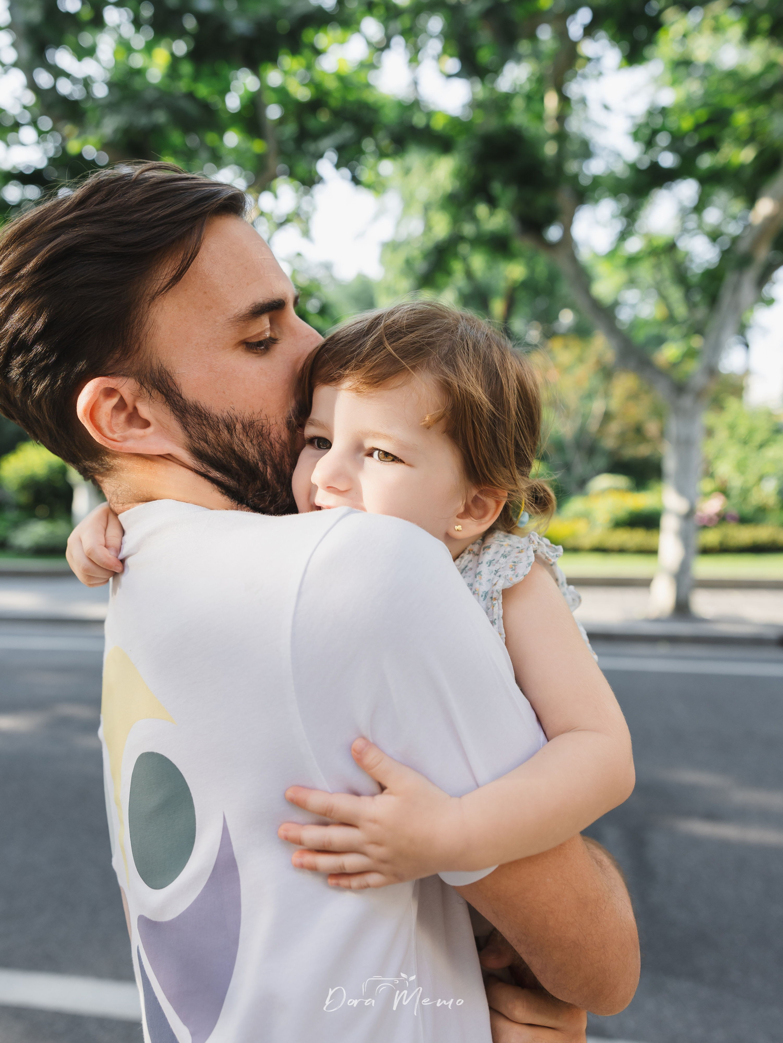 Dad kissing daughter's head | Father gently kissing his young daughter's head, a tender ending to a summer afternoon