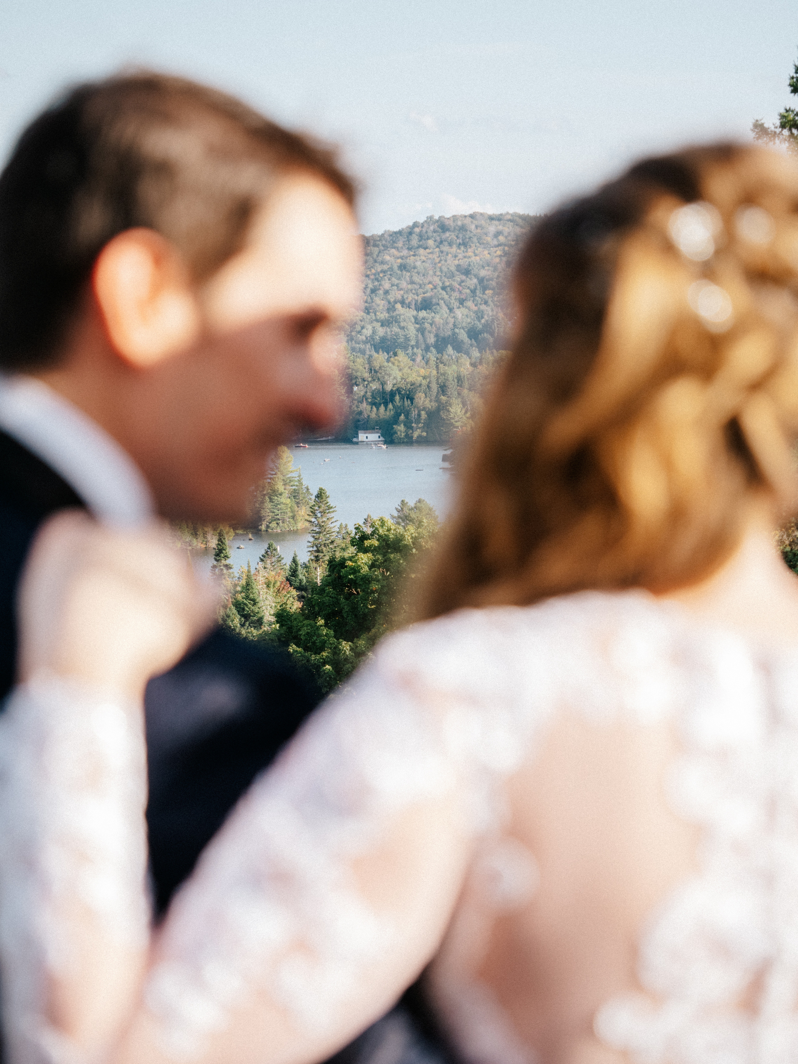 Out of focus photo of couple in front of Laurentian mountains and lake in Sainte-Agathe-des-Monts, Canada.
