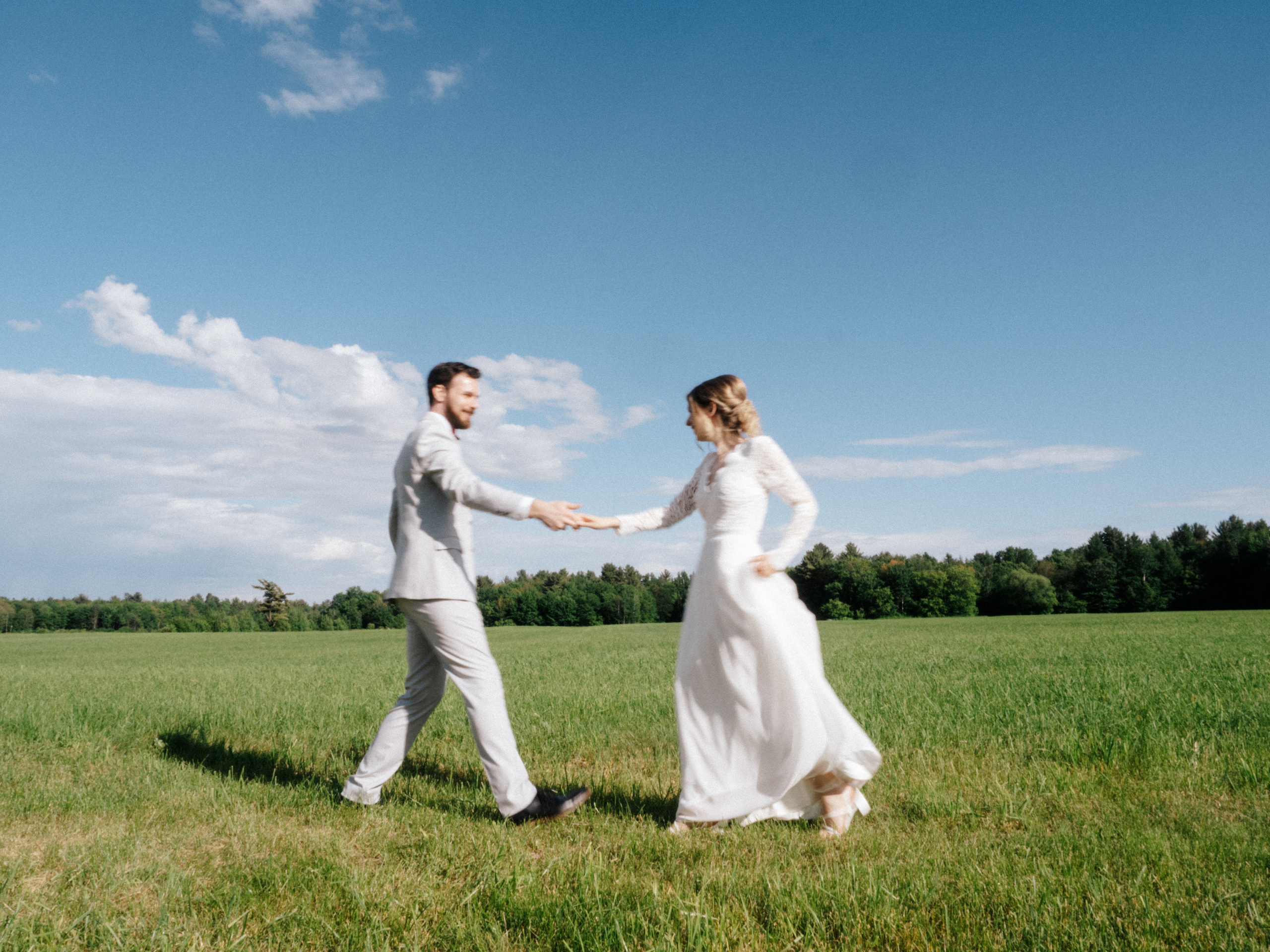 Couple dancing with motion blur in front of field and blue skies.