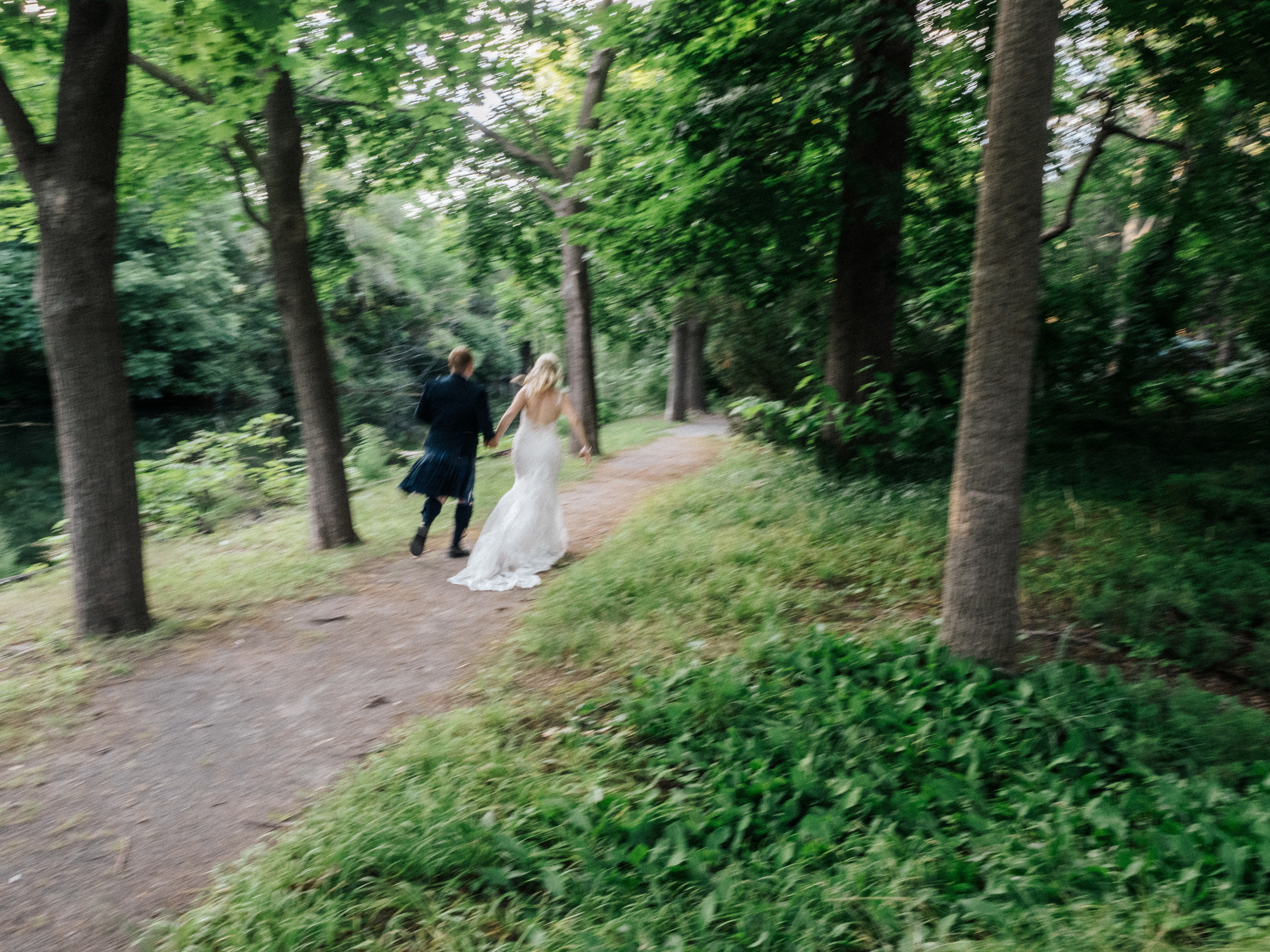 Motion blur photo of couple running in forest on Island Parc Jean Drapeau, Quebec.