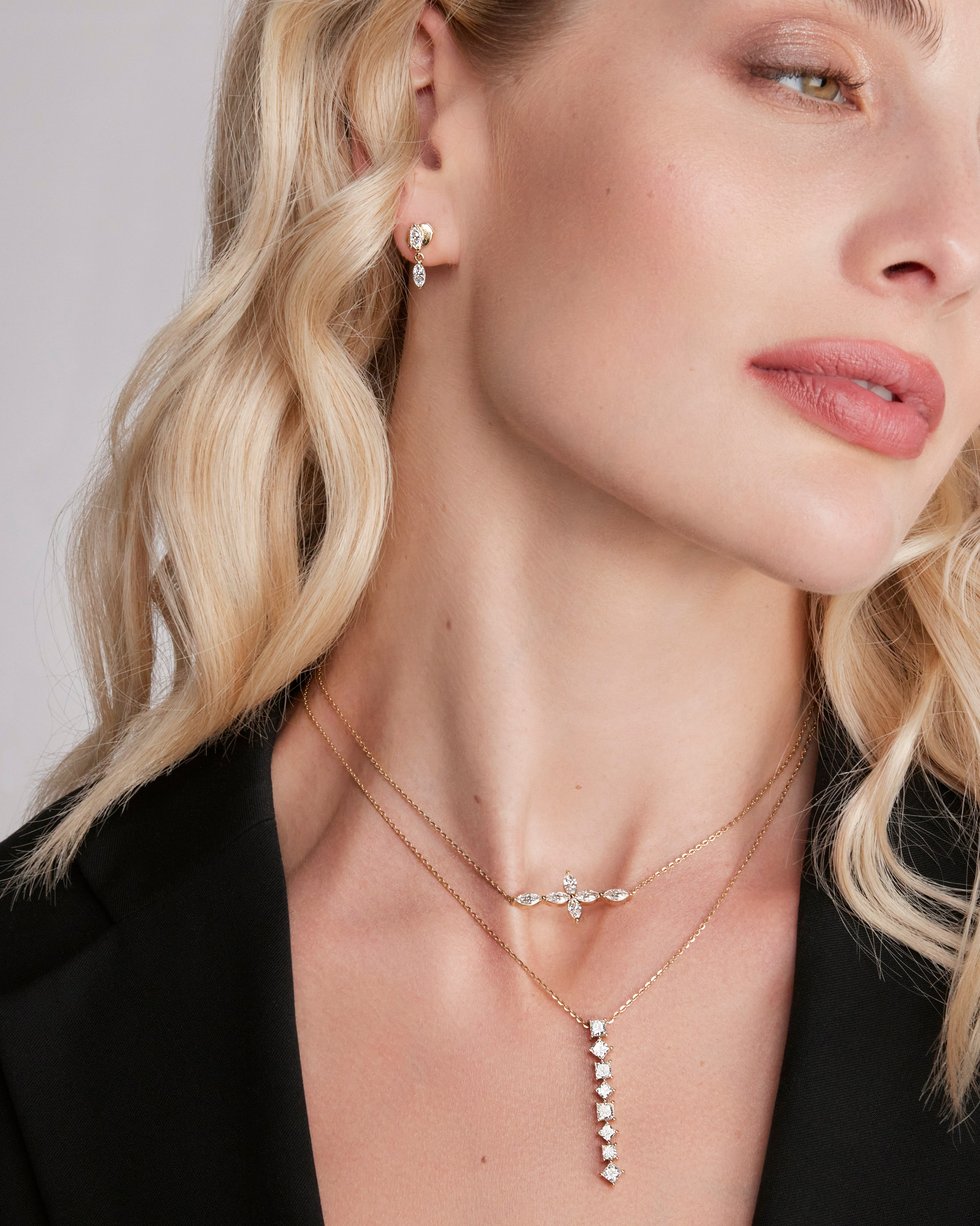 Blonde model wearing layered necklaces and earrings, capturing high-end jewelry fashion.