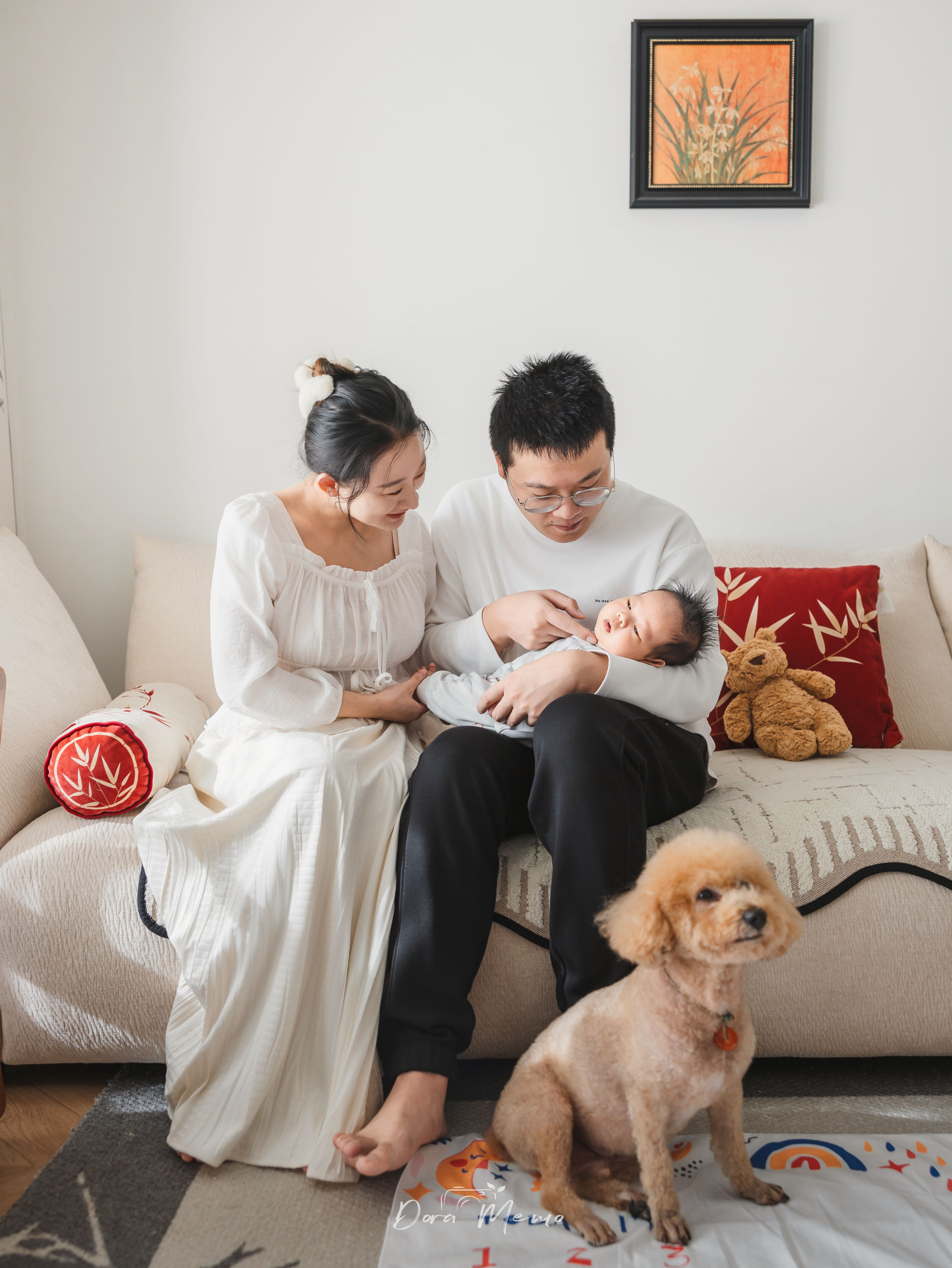 Parents holding their one-month-old baby on the sofa with the family dog nearby, natural and relaxed family photography in Shanghai.