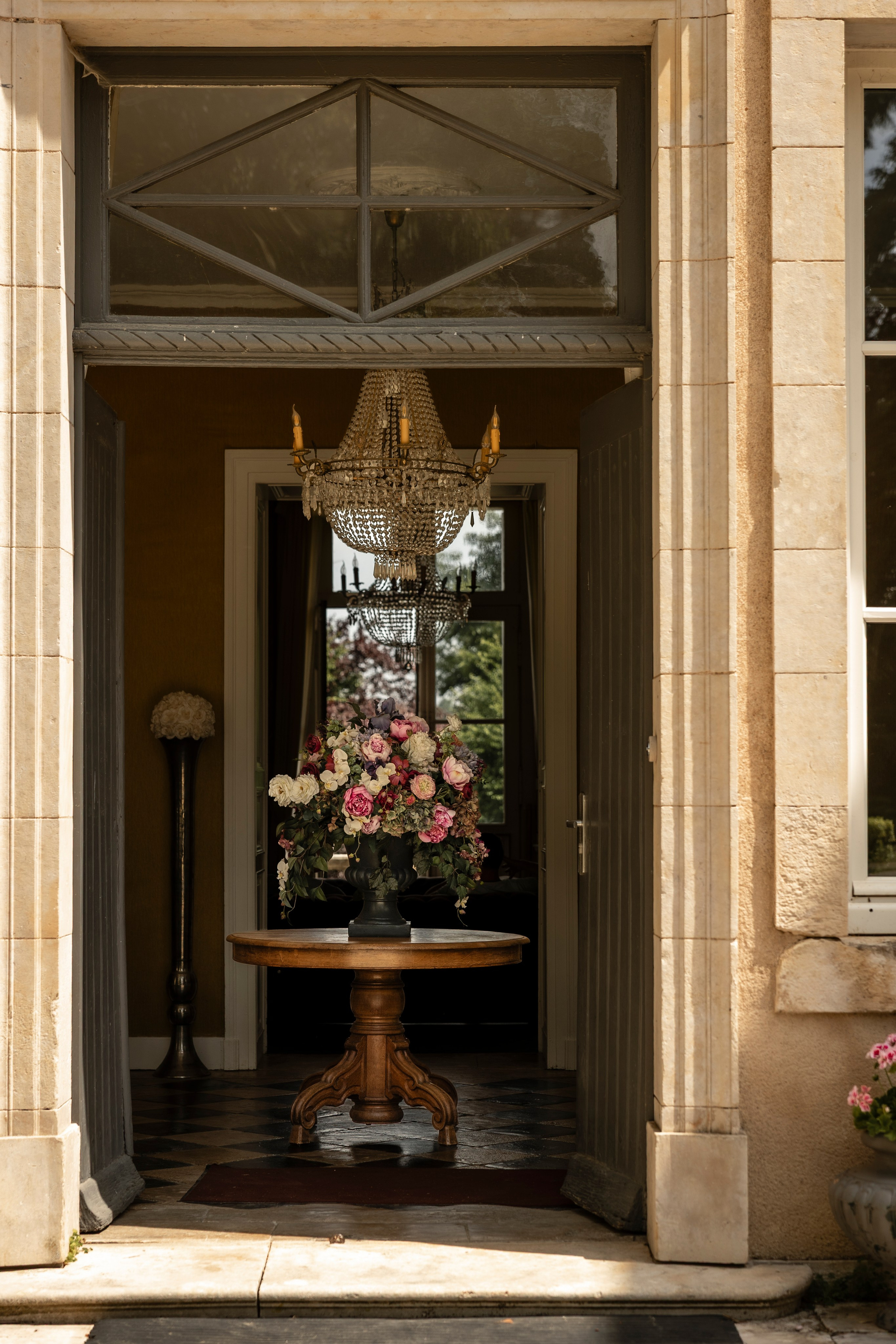 Open château doorway with a flower arrangement on a round table in the entrance hall
