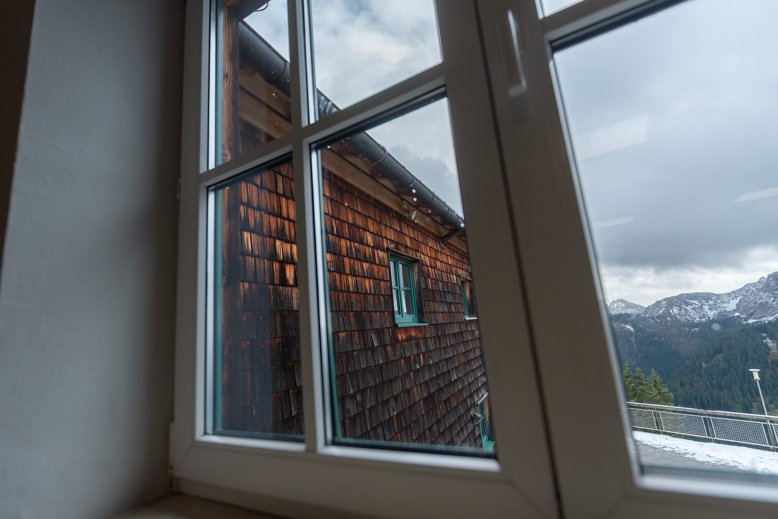A view through the window of Panoramarestaurant Wallberg mountain hotel overlooking the alpine landscape.