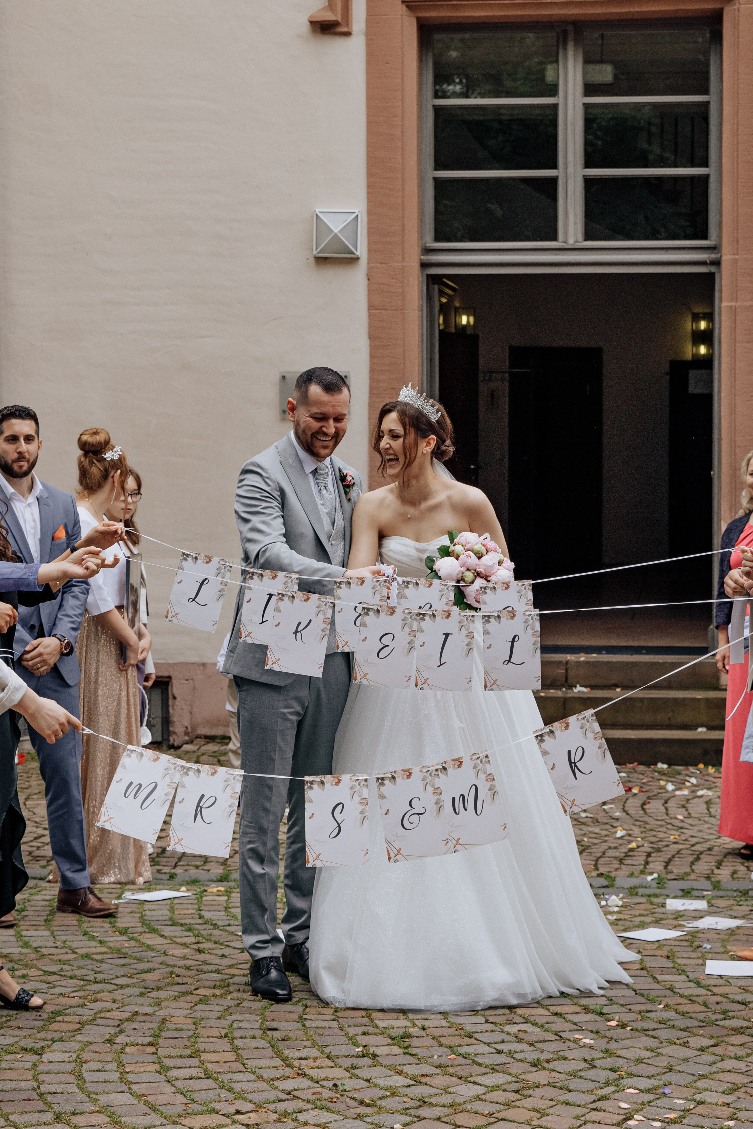 Der Bräutigam und die Braut schneiden gemeinsam die Bänder durch, während die Gäste in einer Reihe stehen.