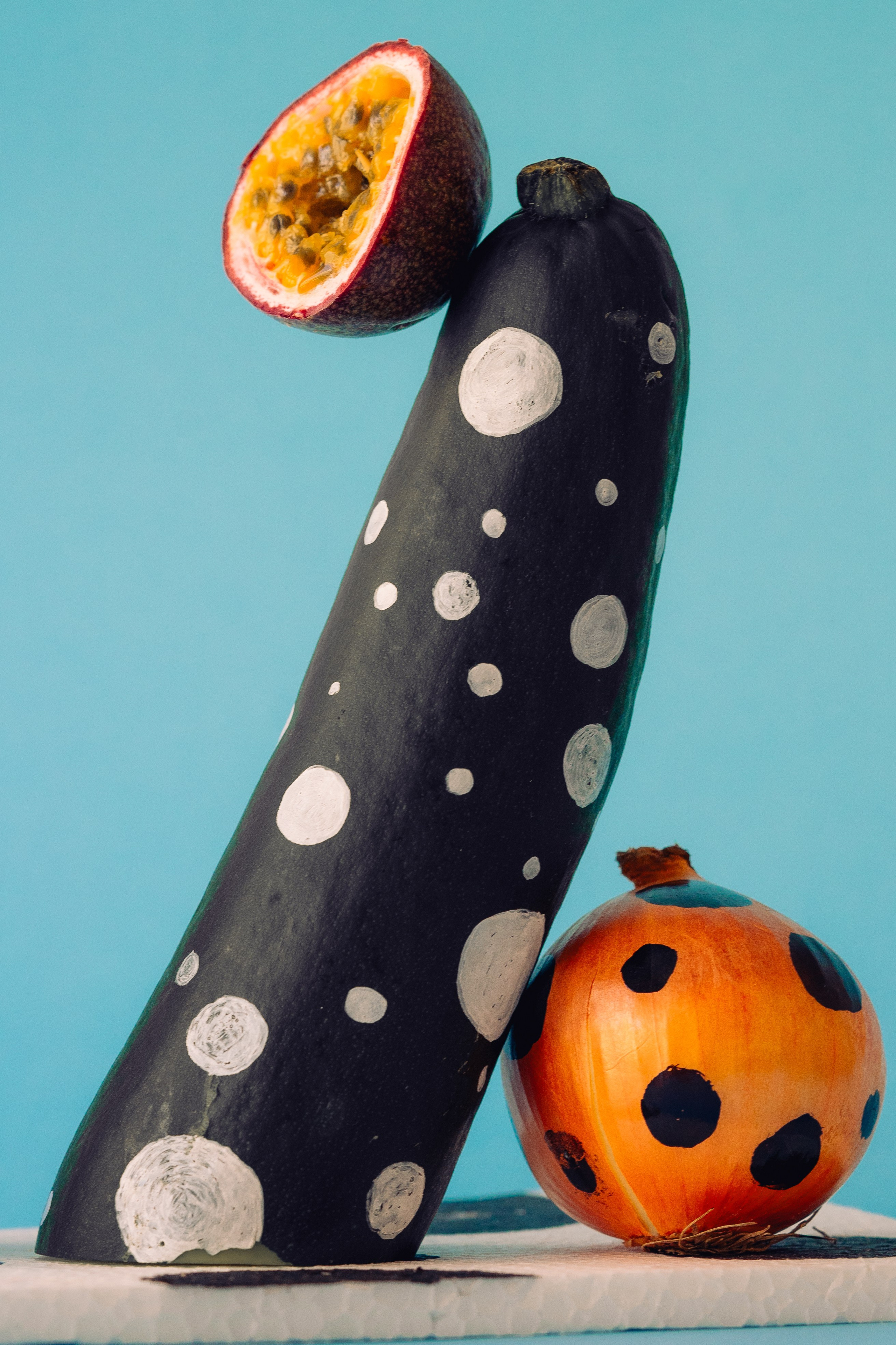 Dotted Design Painted Vegetable Art Arrangement.  Creative display of dotted design painted vegetables on a bright blue backdrop.
