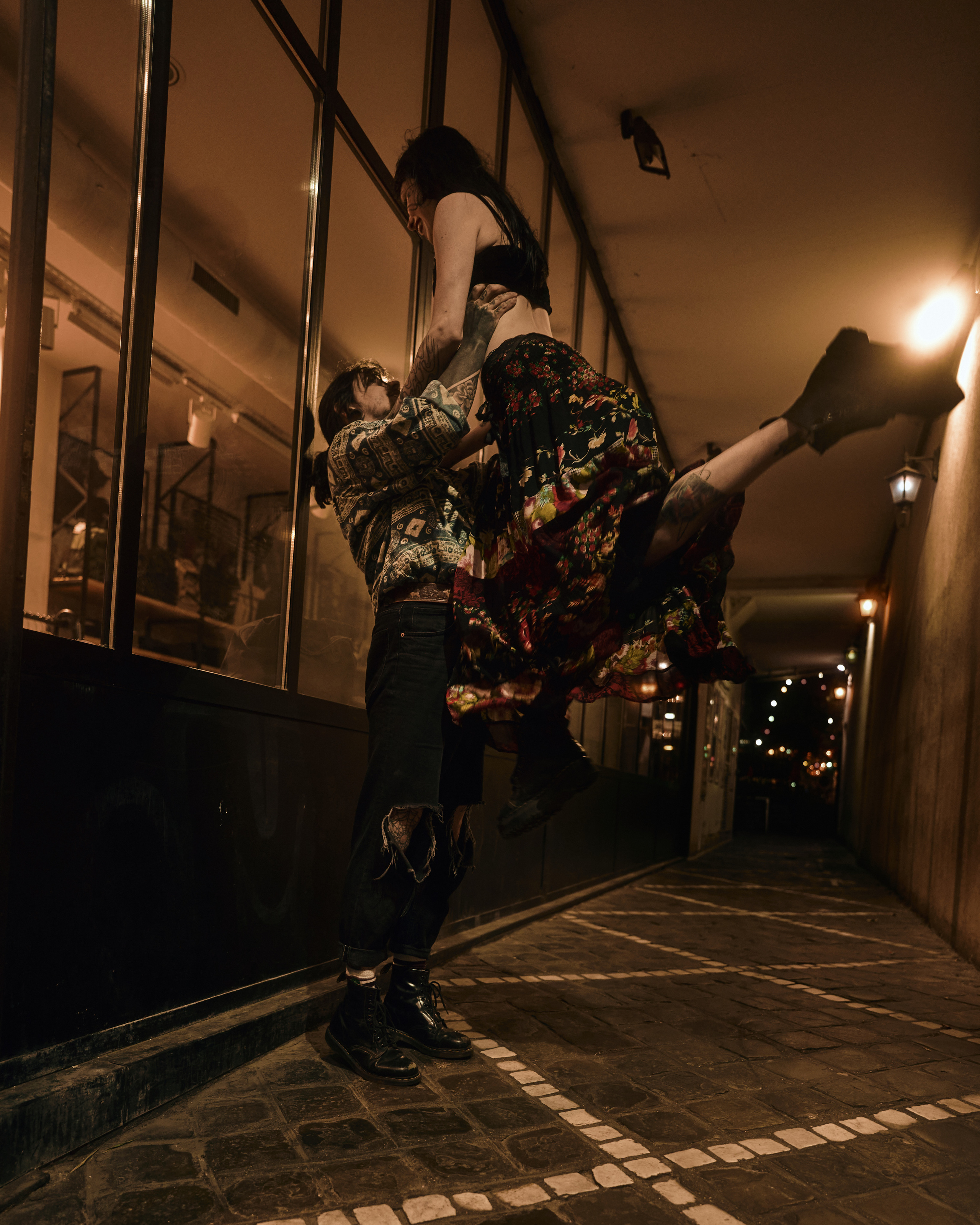  A dynamic photo of a dancer mid-movement in an urban setting, illuminated by warm, industrial lighting.