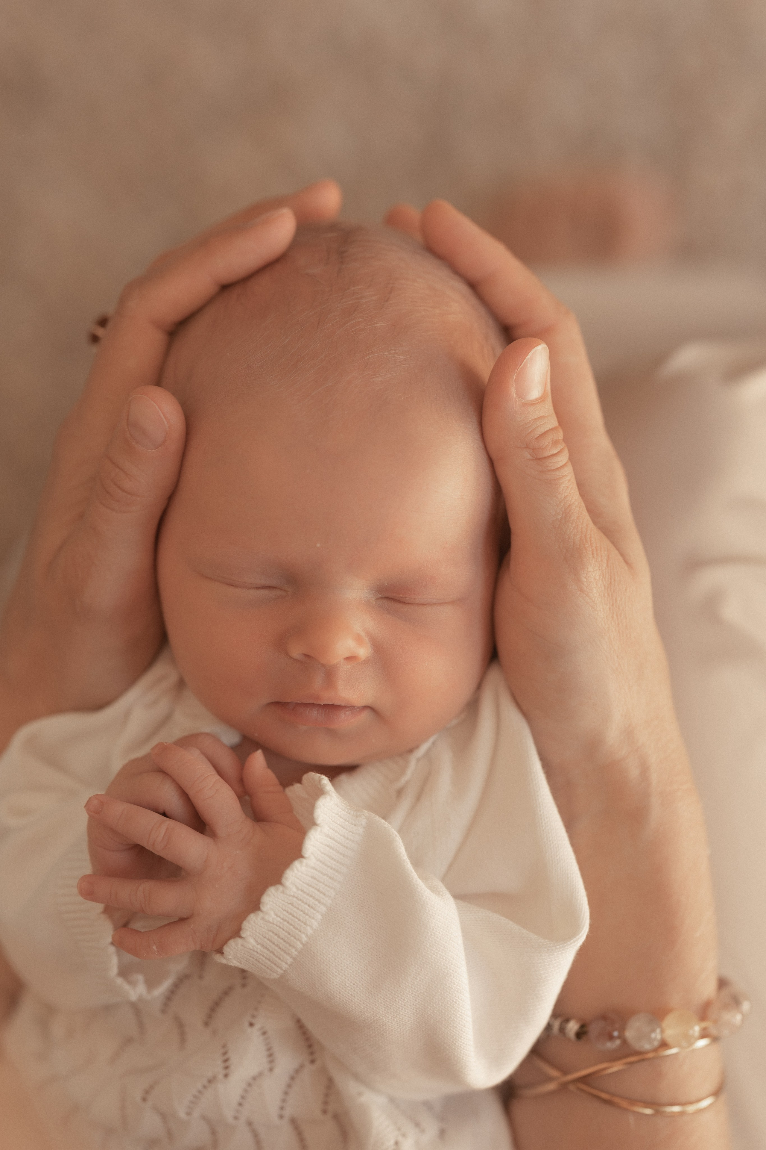 Neugeborenes in Mutterhänden eingekuschelt – professionelles Neugeborenen-Shooting in Salzburg.