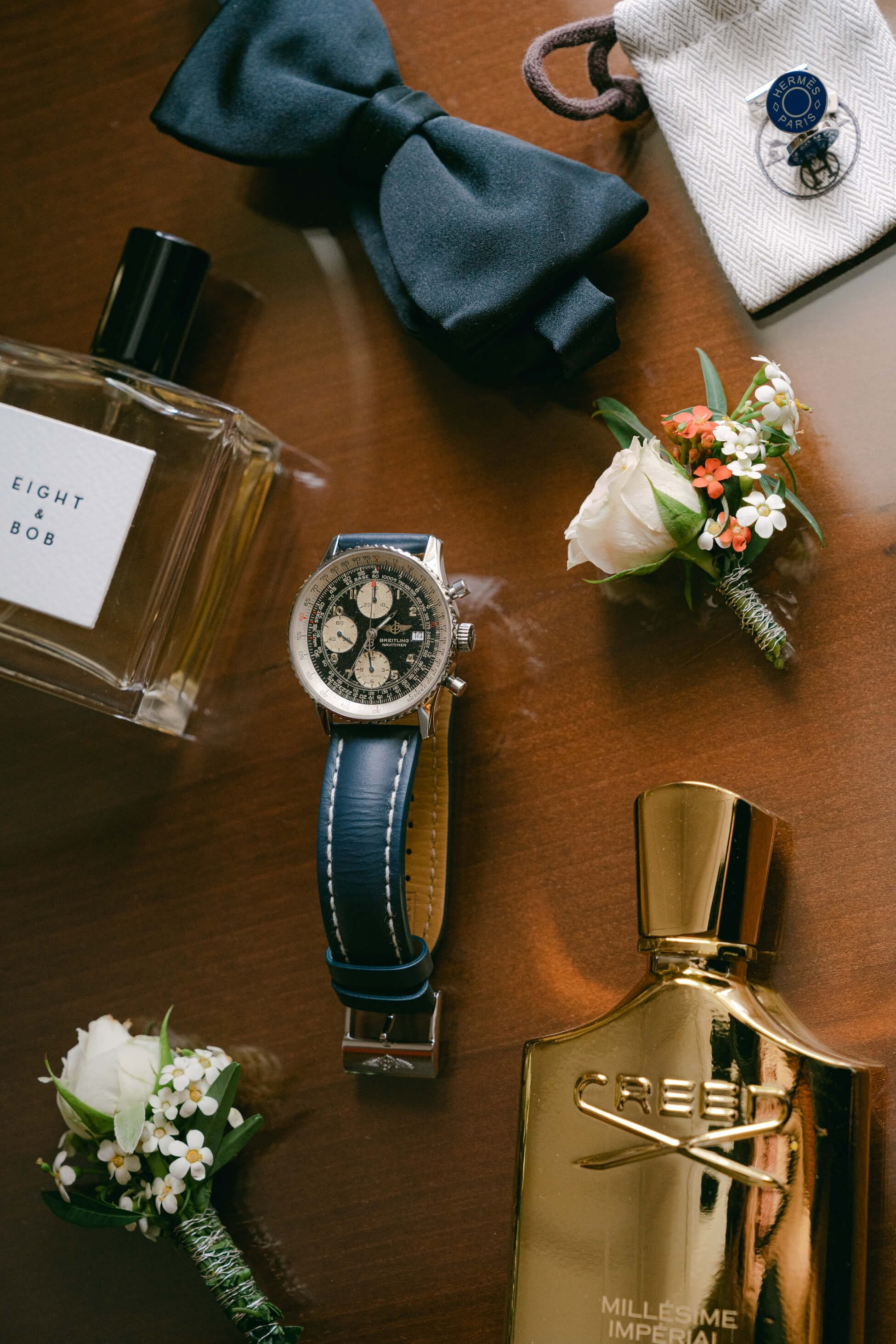 Groom's wedding accessories flat lay with bow tie, Breitling watch, cufflinks, cologne and boutonnière, black tie wedding Frankfurt Villa Rothschild