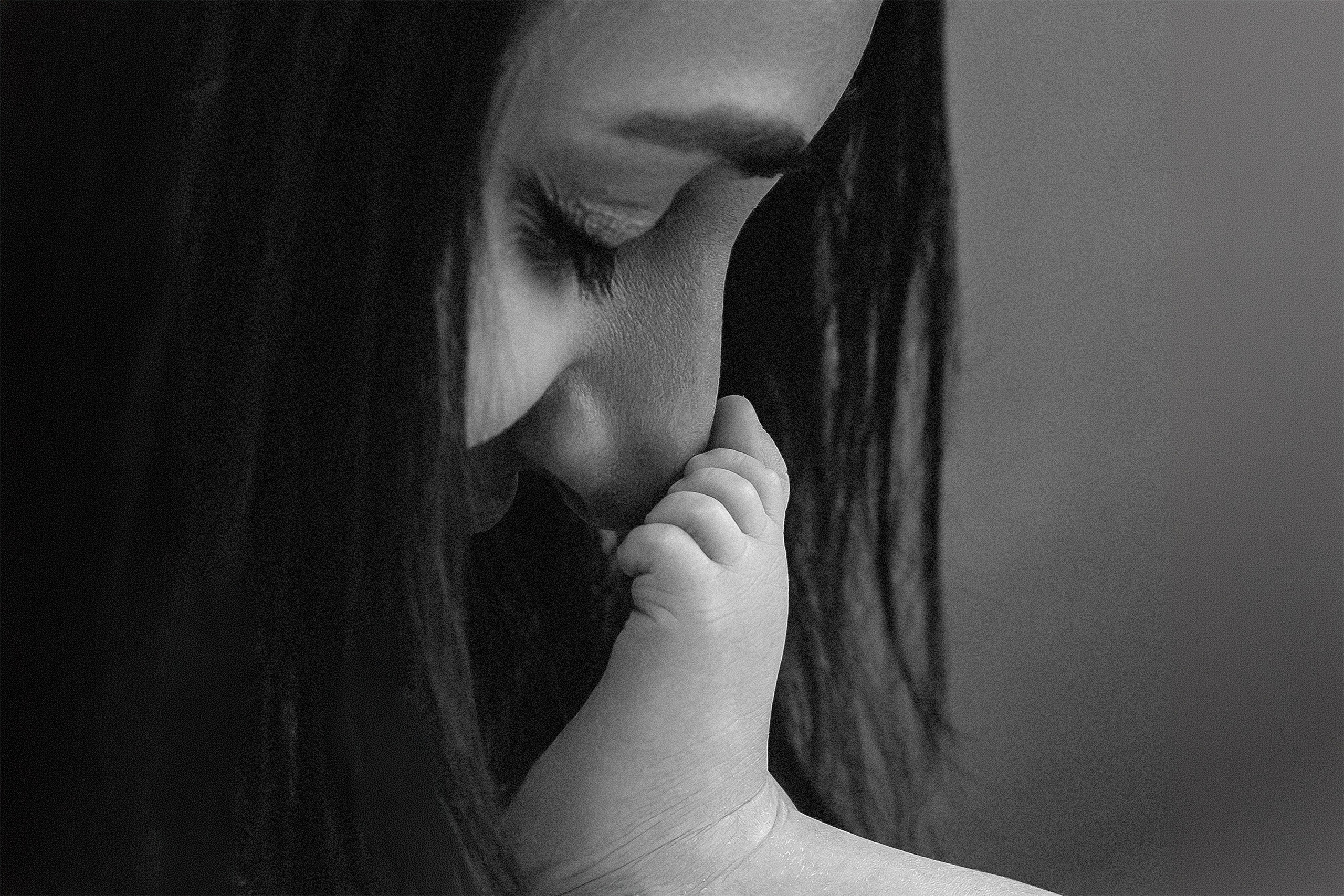 Семейная фотосессия в Валенсии, Испания, с нежным чёрно-белым крупным планом, где мама целует ручку своего малыша, передавая интимную и эмоциональную связь между родителем и ребёнком — идеально для семейной и newborn-фотографии в Валенсии и по всей Испании.