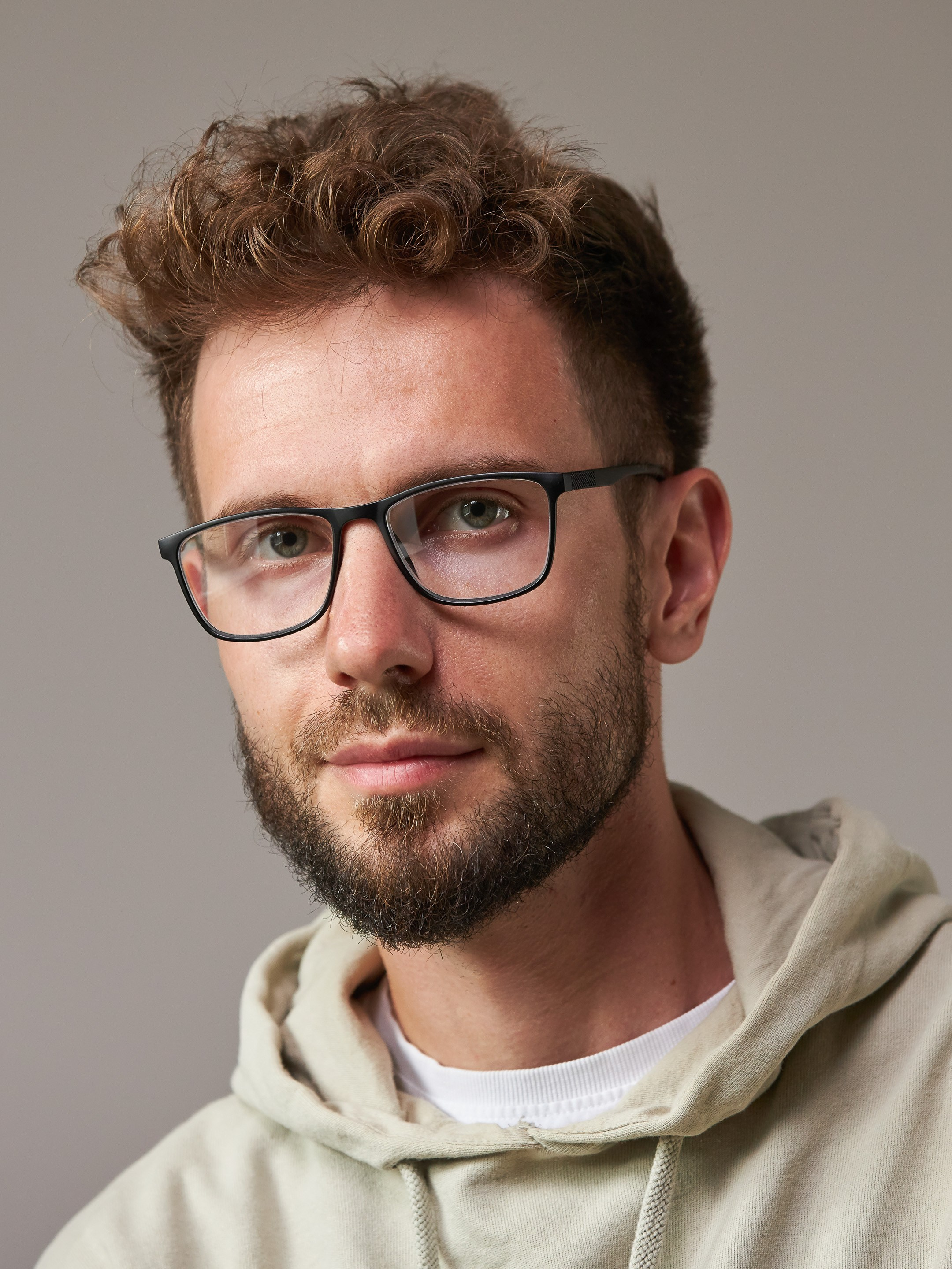 Eyewear model photoshoot - studio portrait of a young man on warm grey background - photographer Andrey Dunin