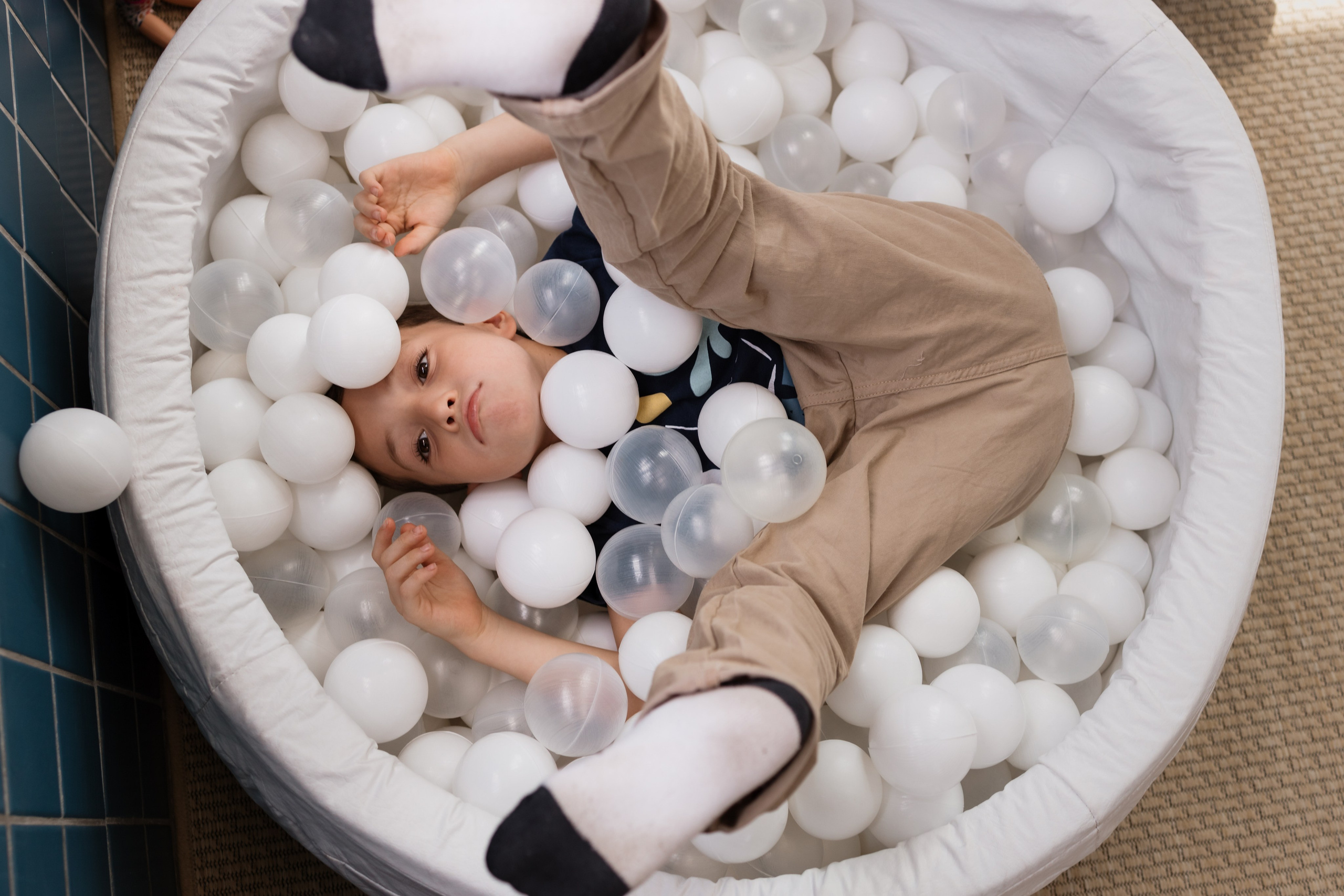 Menino com os pés para cima na piscina de bolinhas