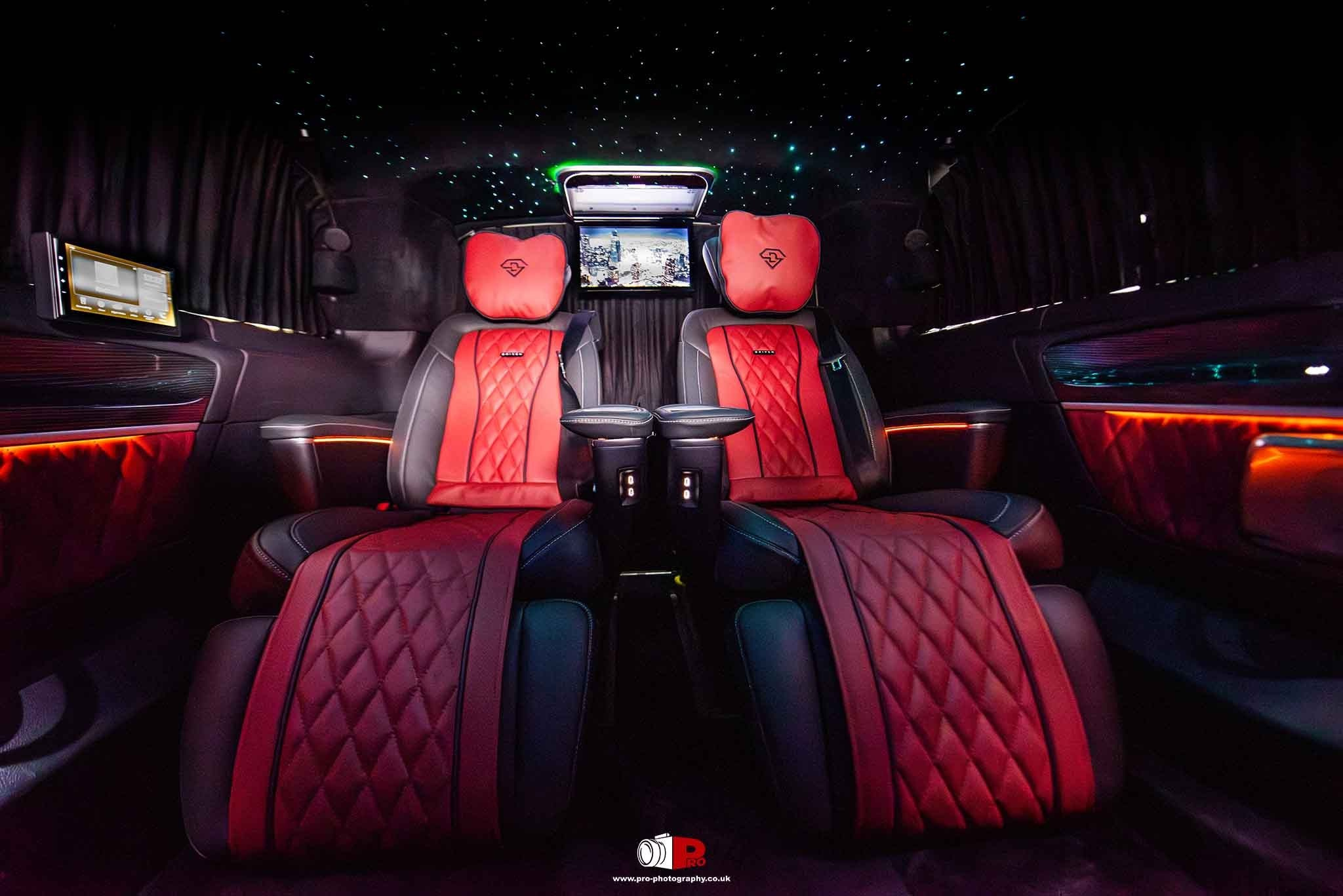 Custom luxury van interior with red quilted leather seats, ambient lighting and a star-effect ceiling.