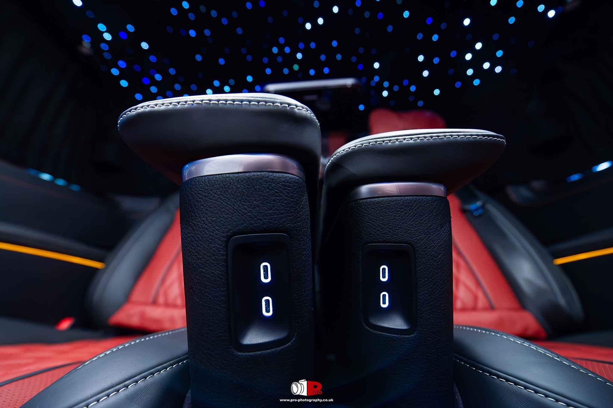 Automotive detail image of illuminated electric seat controls and ambient lighting inside a luxury vehicle.