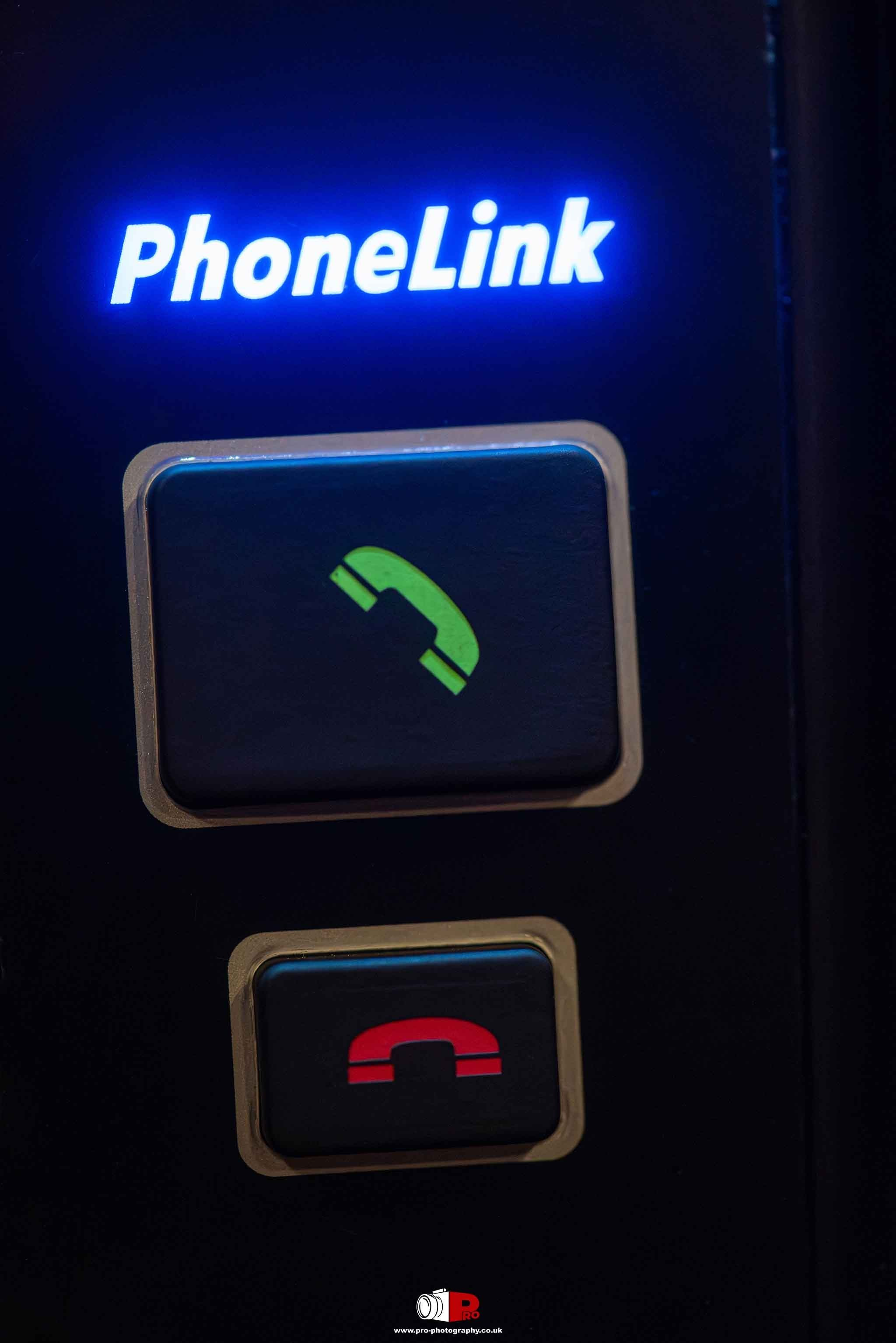 Close-up automotive image of illuminated PhoneLink call and hang-up controls inside a luxury vehicle.