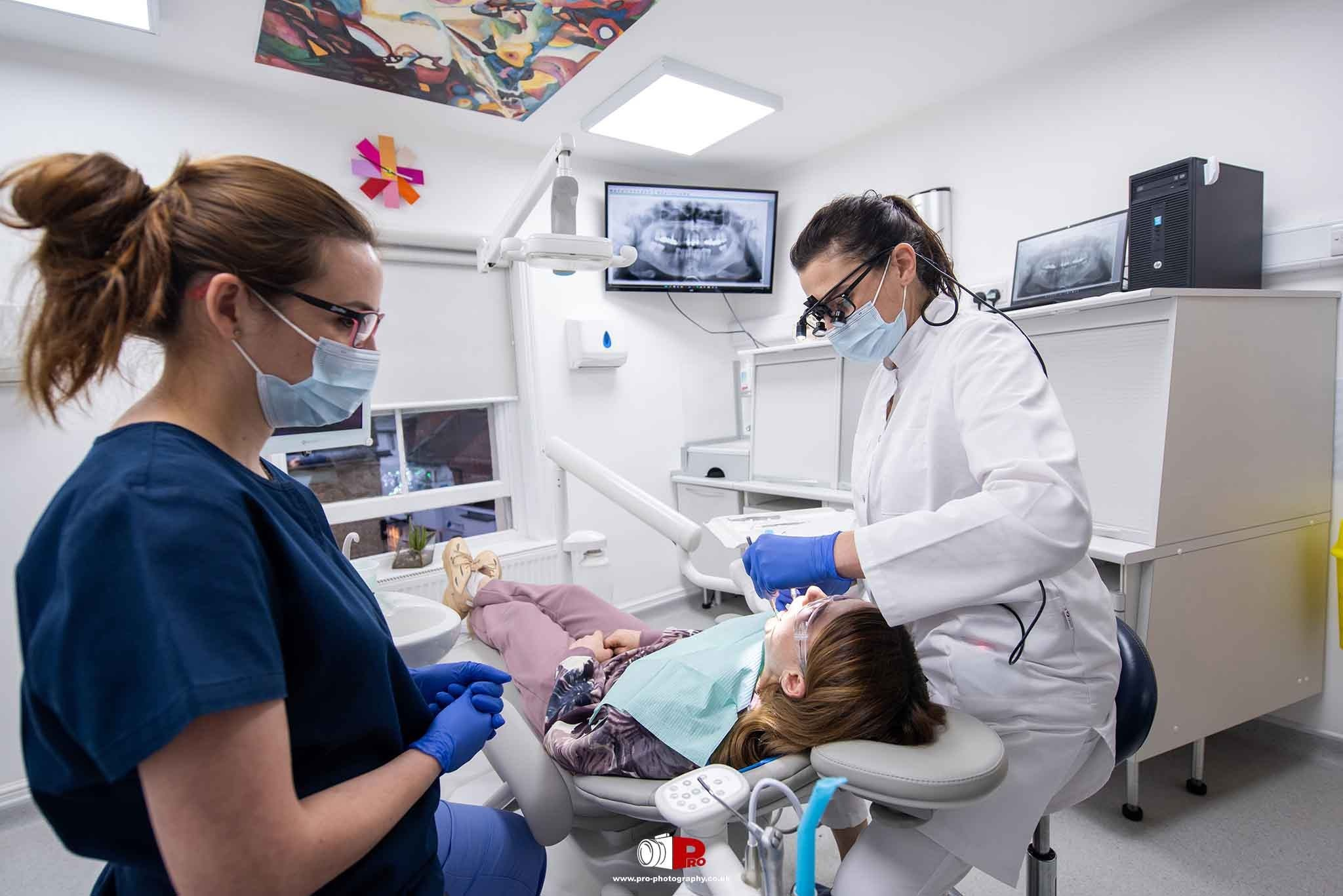 Commercial healthcare image of a dentist and dental assistant treating a patient inside a modern dental practice.