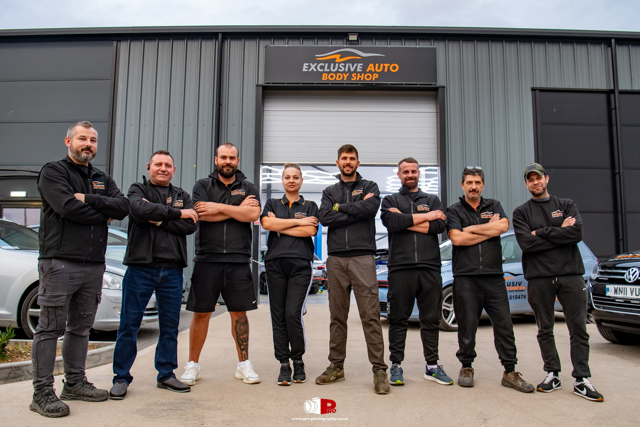 Professional commercial team portrait of Exclusive Auto Body Shop staff photographed outside their workshop.
