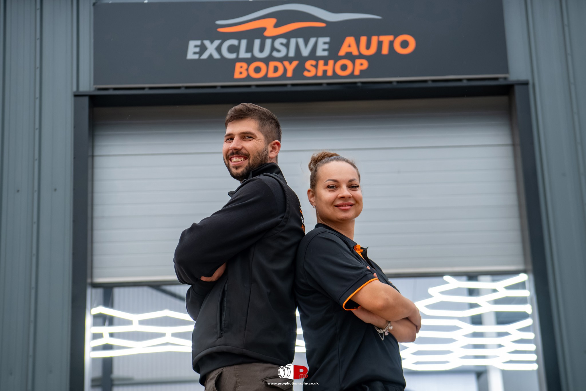 Professional environmental portrait of two automotive body shop staff standing outside the Exclusive Auto workshop.