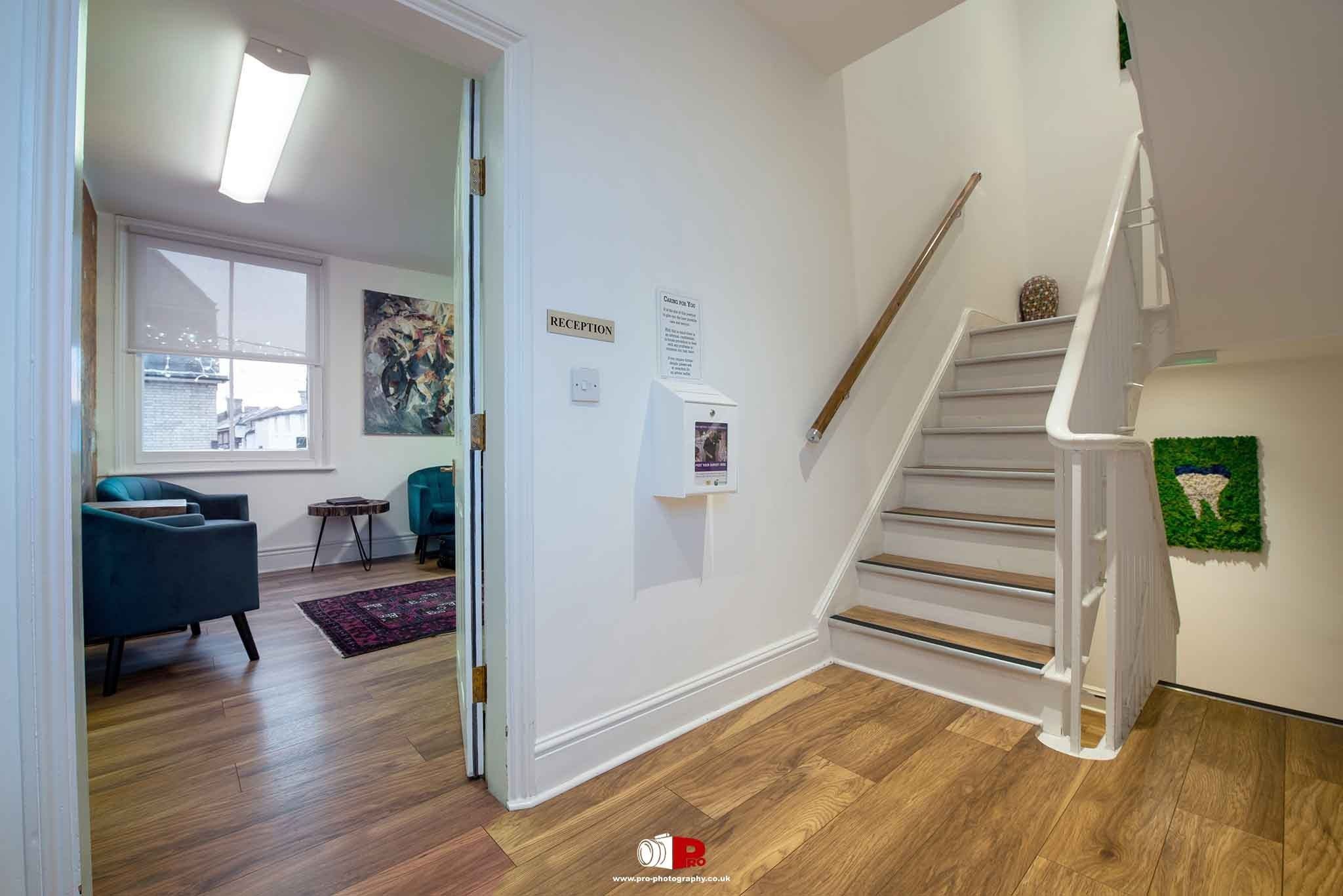 Commercial interior image showing a modern clinic reception area, staircase and waiting room.