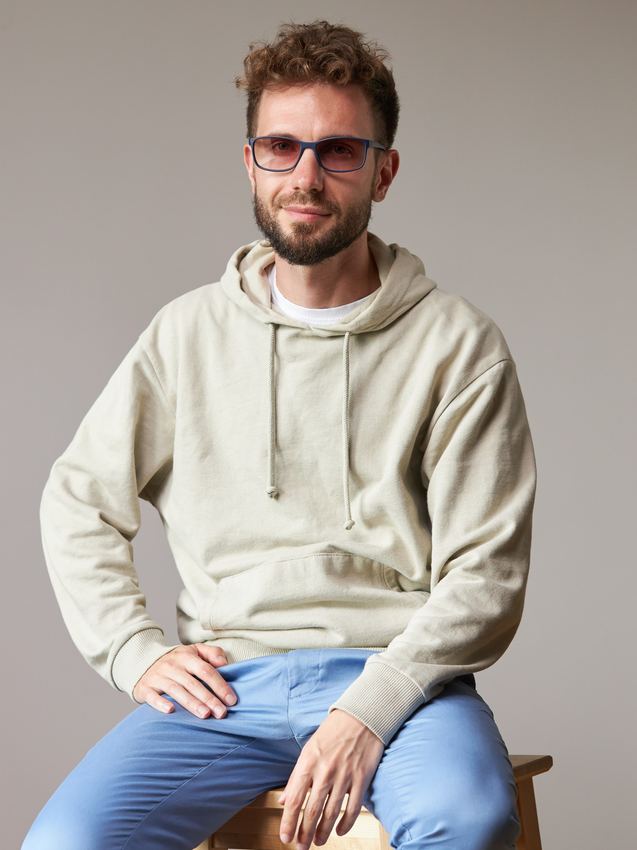 Eyewear model photoshoot - studio portrait of a young man on warm grey background - photographer Andrey Dunin