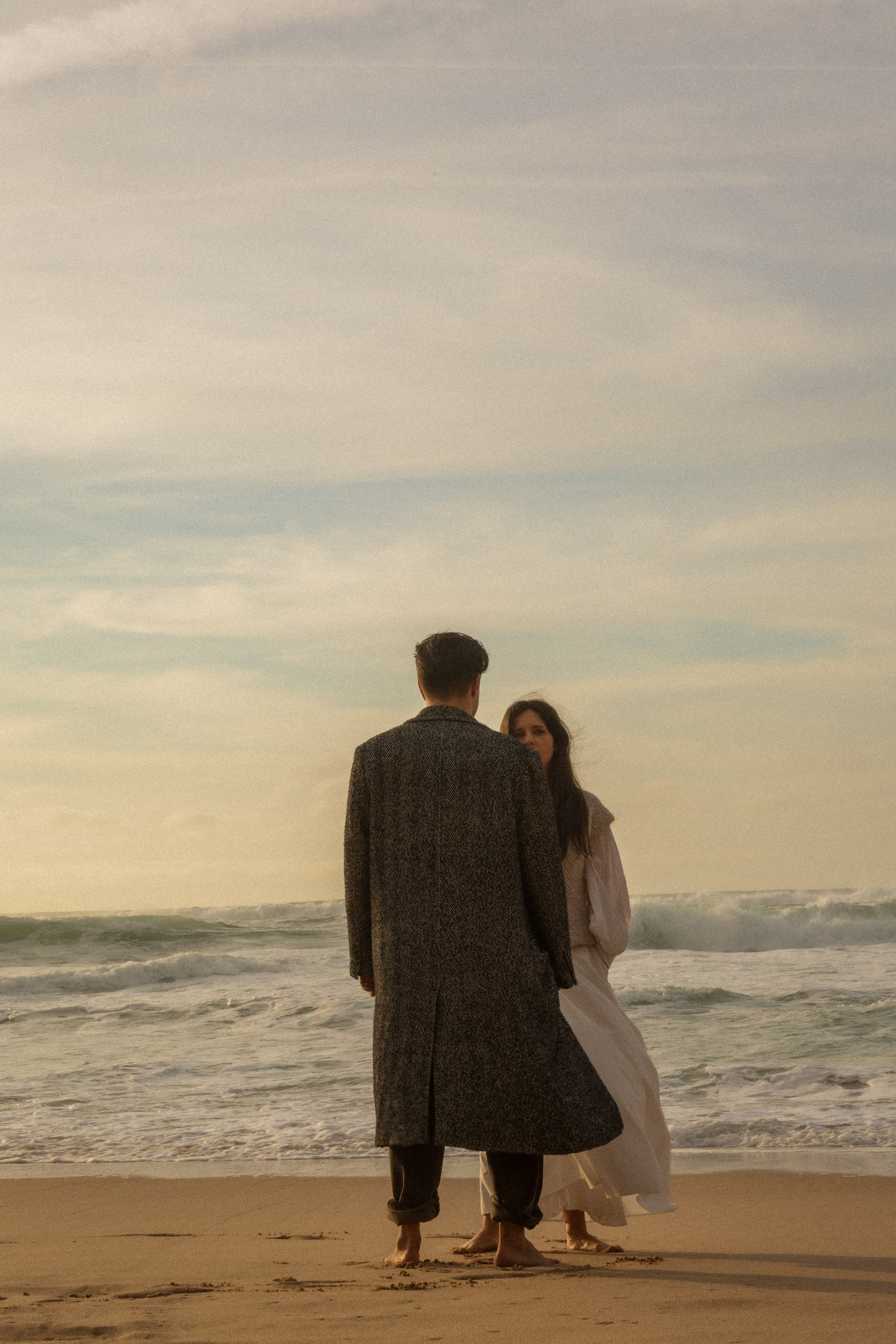 Couple holding hands and walking through a picturesque coastline in Portugal.