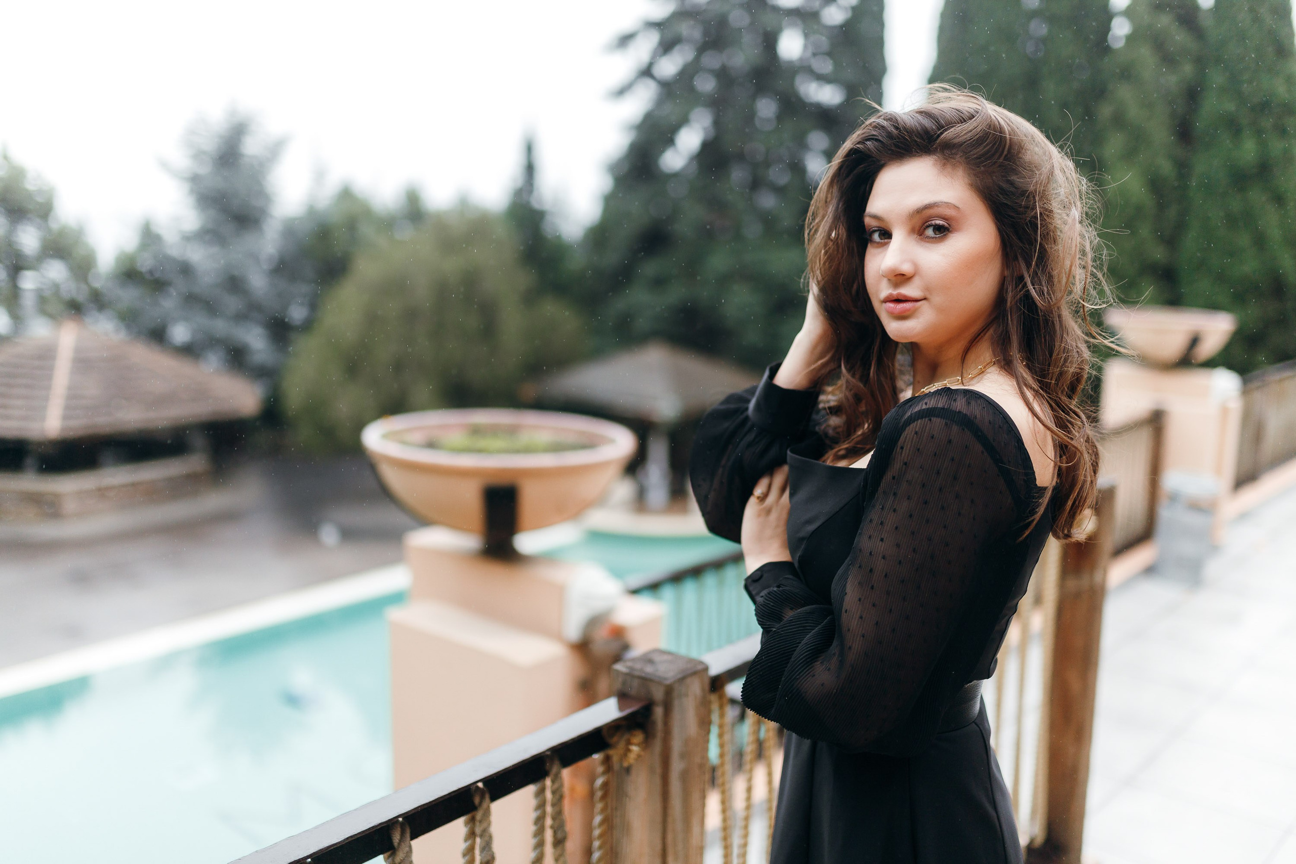 Woman in black dress leaning on wooden railing