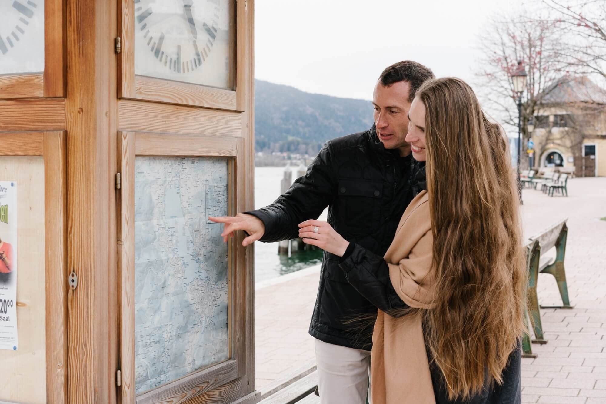 Couple sitting at a terrace café table by a Bavarian building with Tegernsee lake view in background Germany