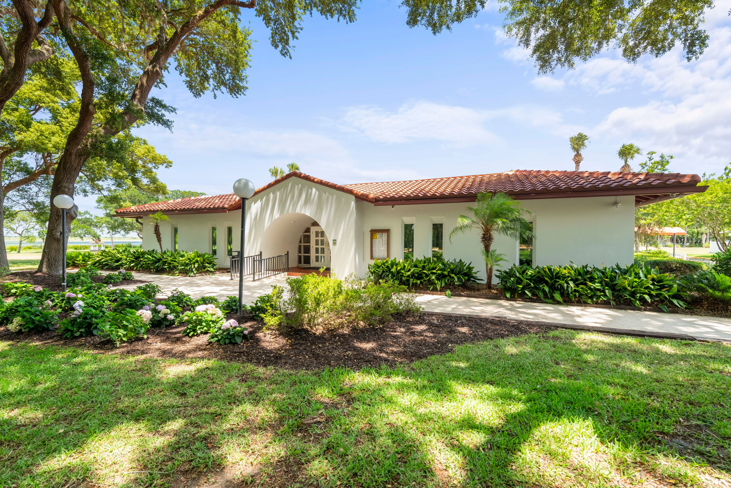 Elegant white clubhouse with red tile roof and tropical garden