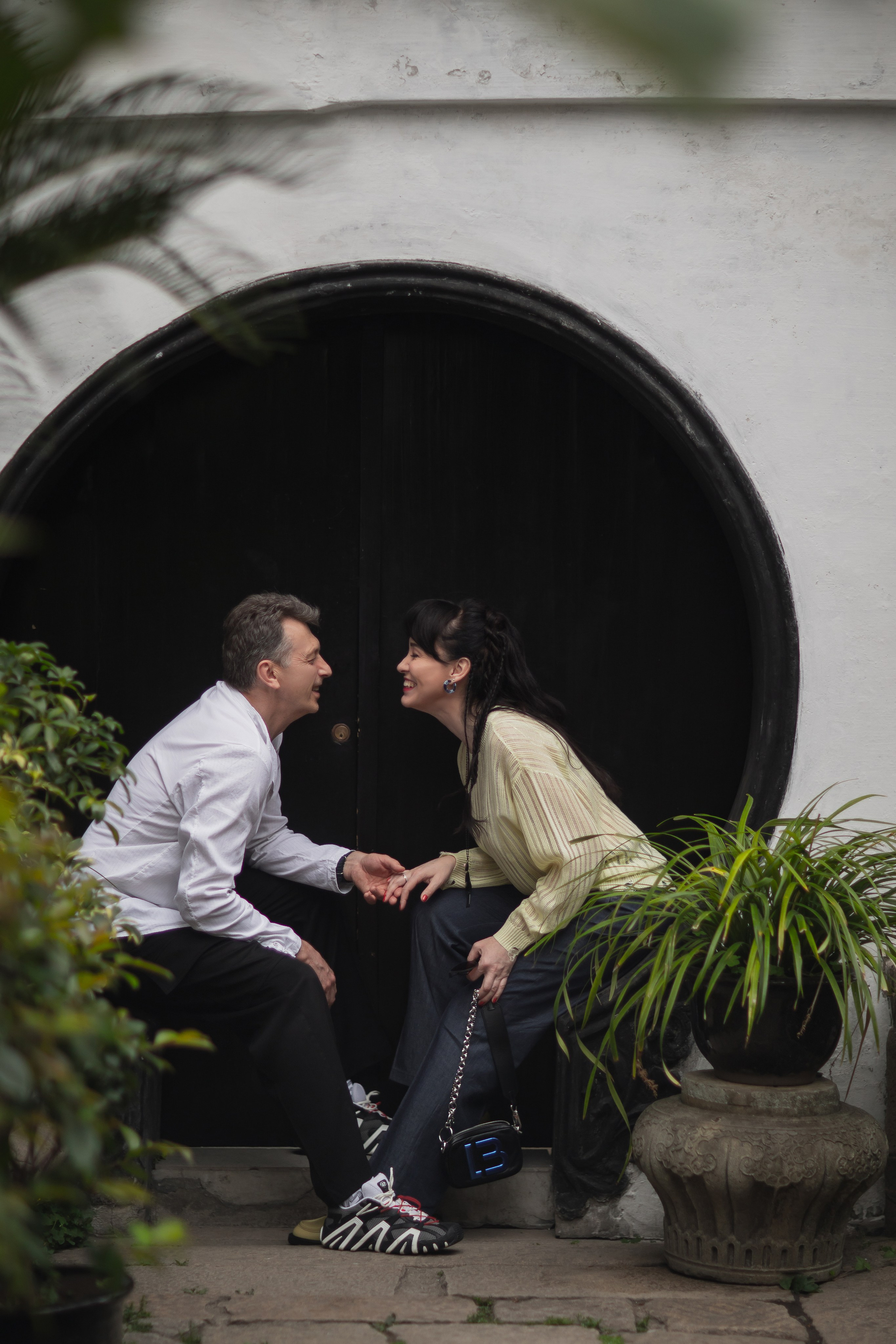 Пара держится за руки в живописном саду Юй Юань 