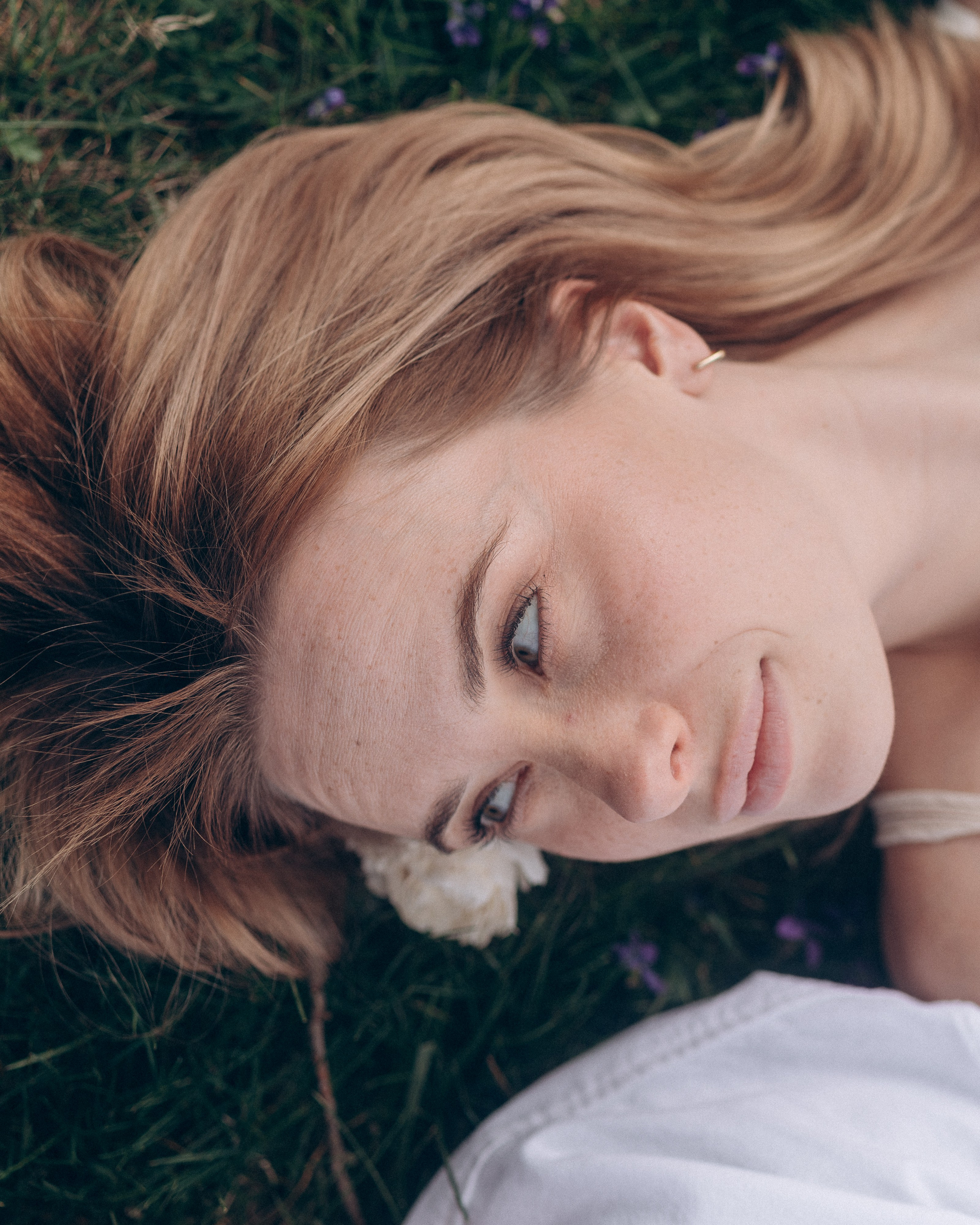 Dreamy close-up of a woman lying in green grass, Ohio engagement shoot