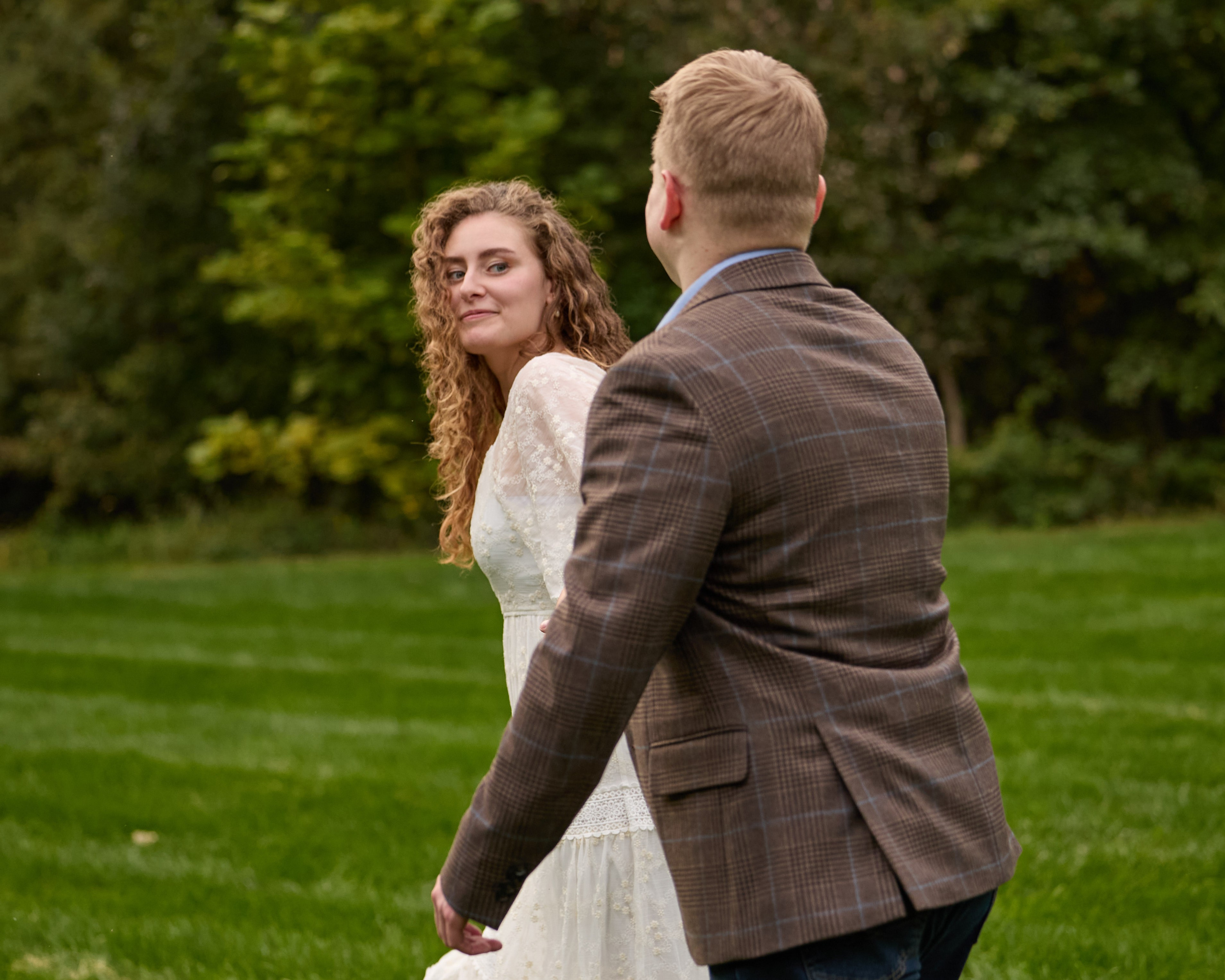 Playful twirl on the lawn during an engagement session at Swan Lake Event Center
