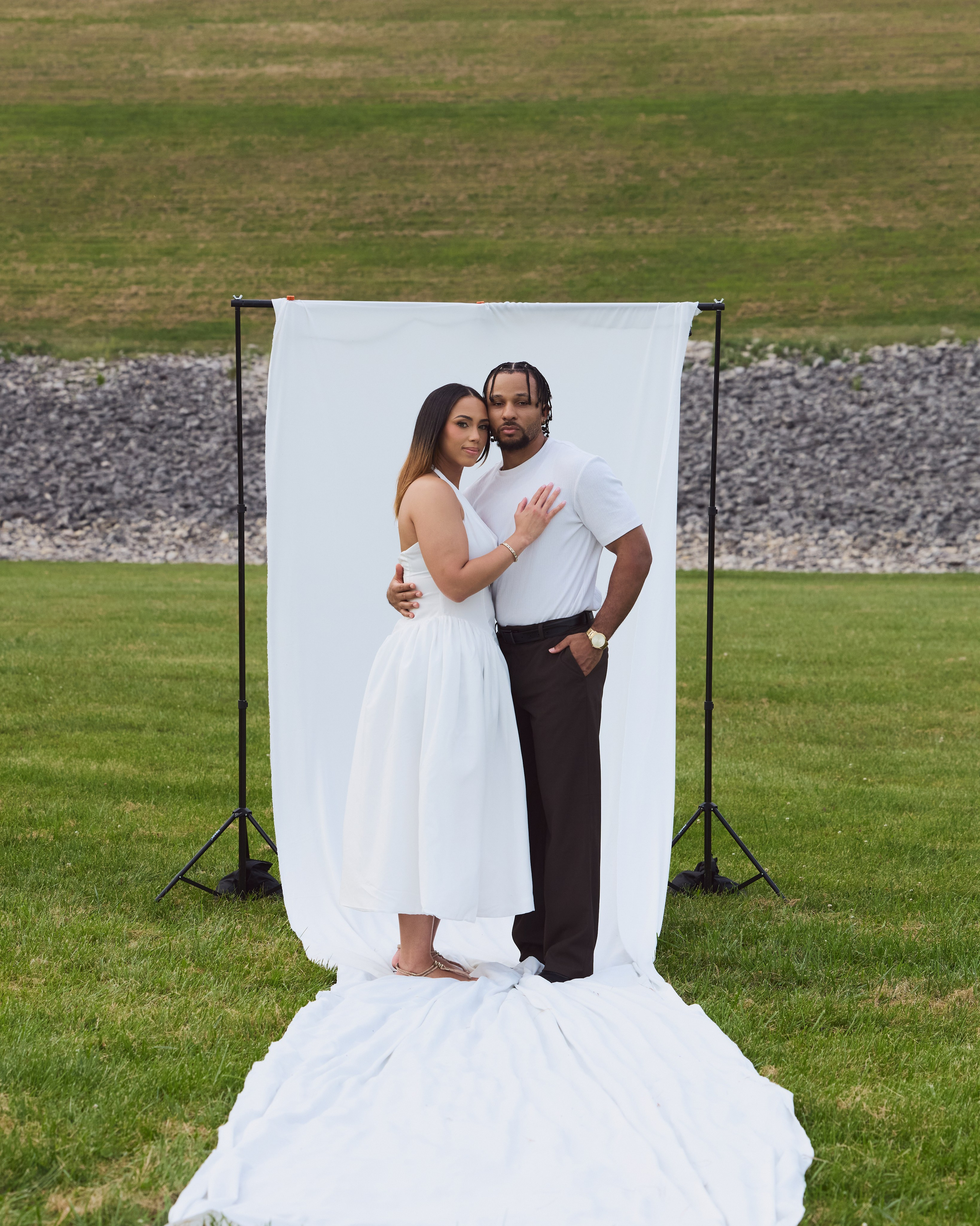 Wide shot of a couple kissing in front of a white backdrop at Alum Creek, Ohio
