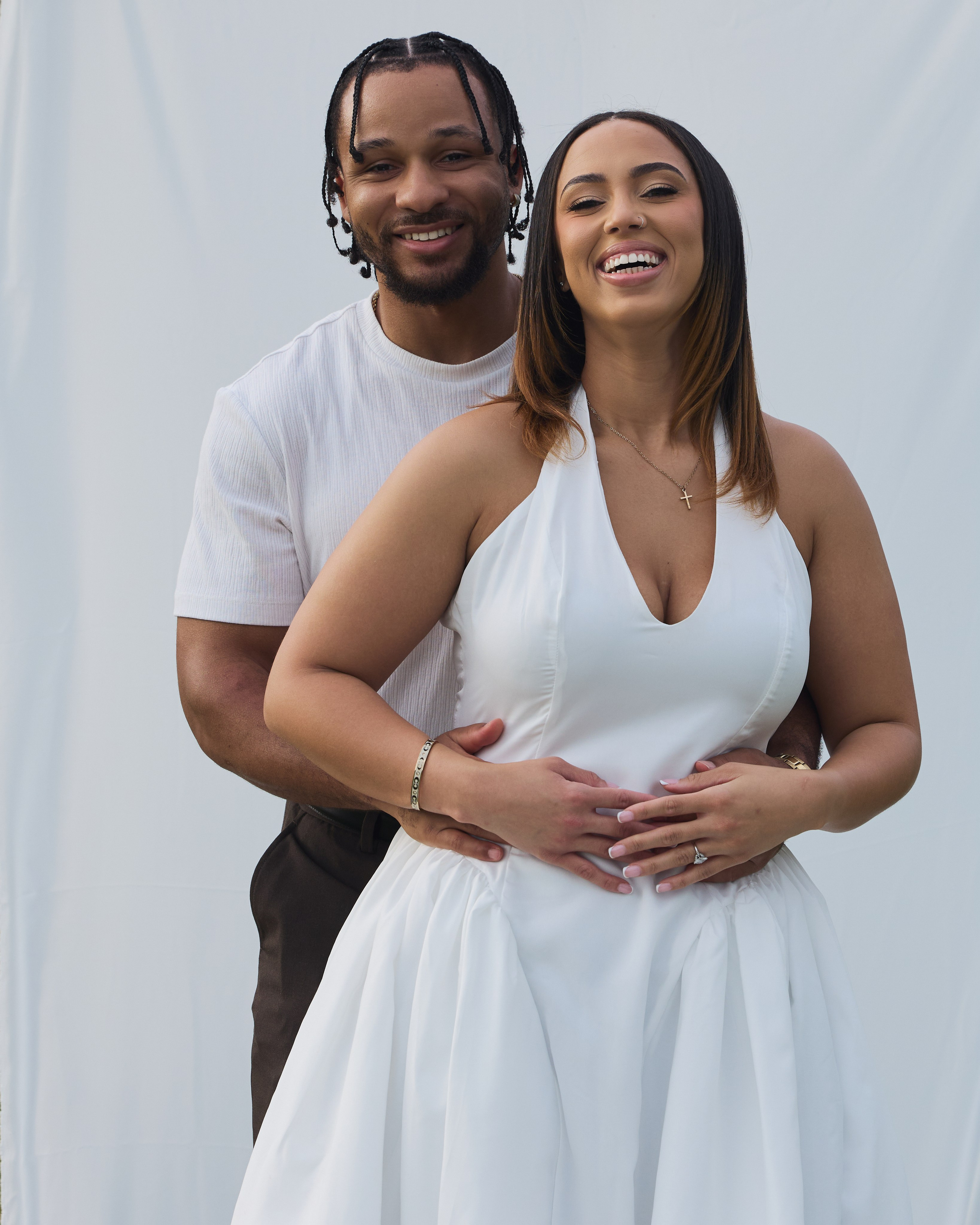 Close embrace of an engaged couple against a white outdoor backdrop at Alum Creek