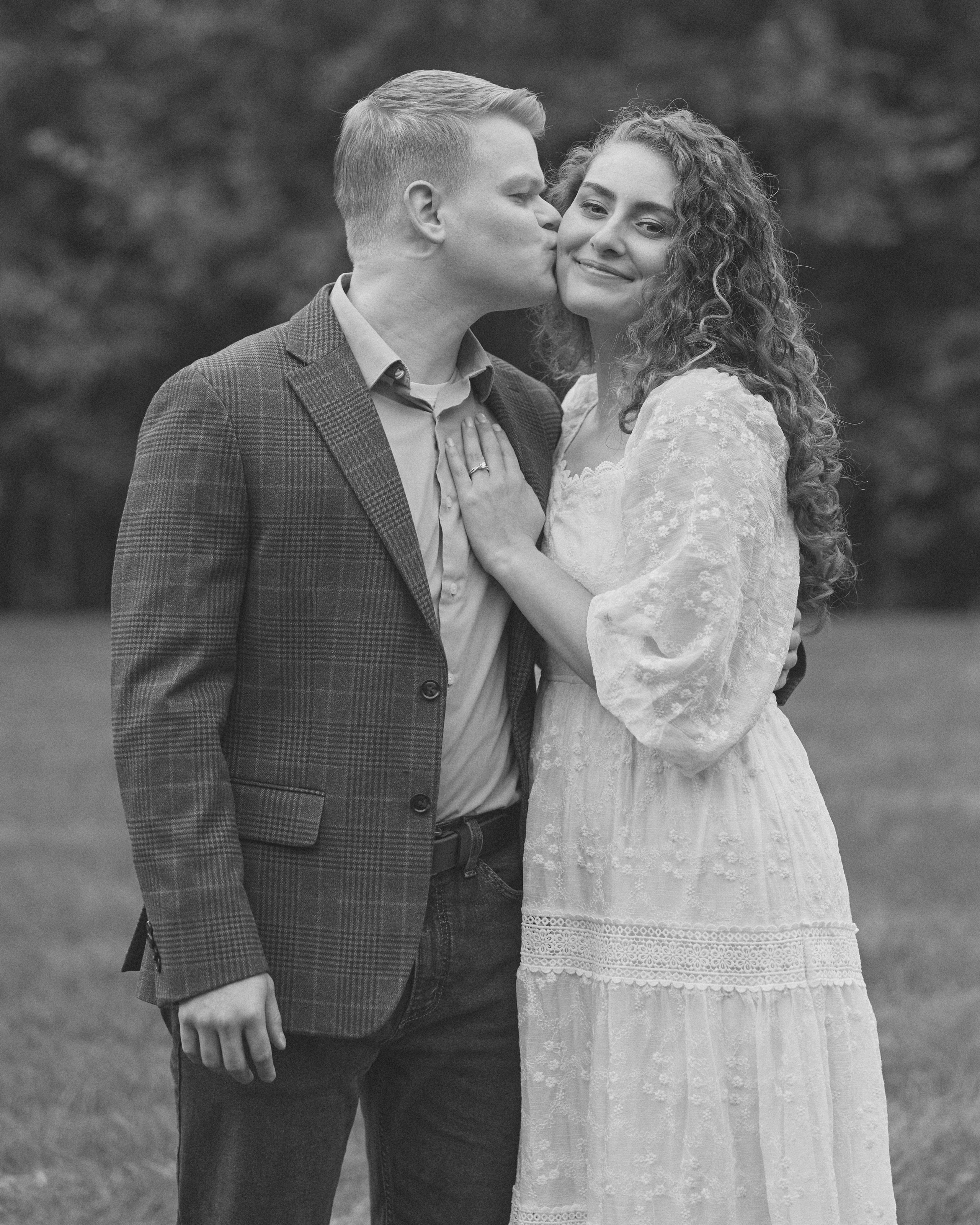 Black and white photo of a kiss on the cheek at Swan Lake Event Center near Columbus