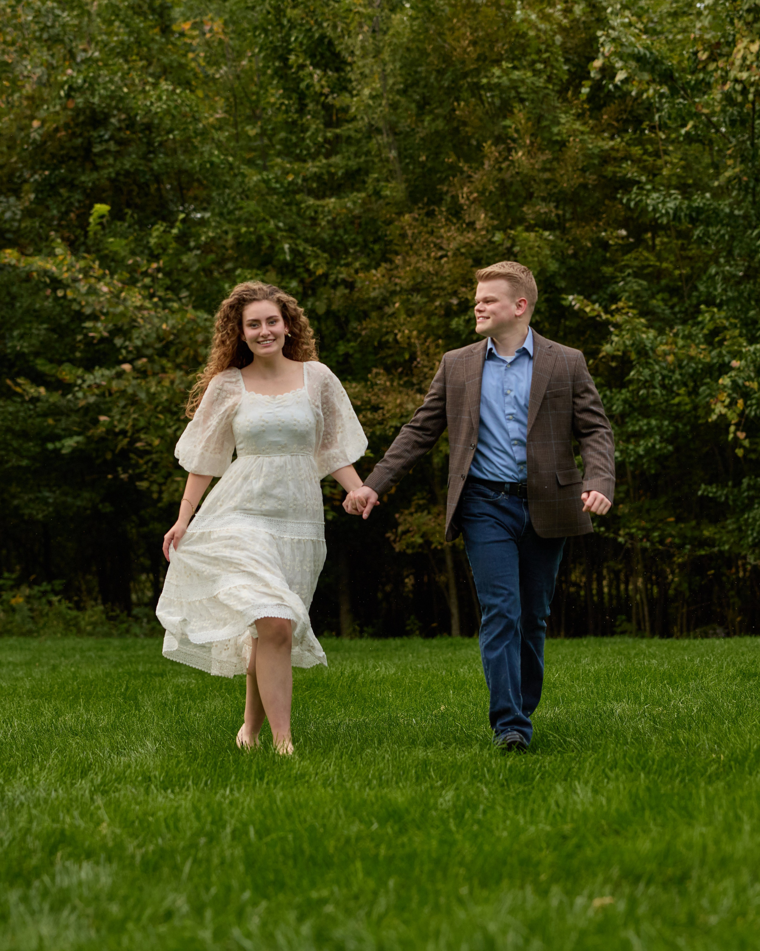 Engaged pair strolling toward the camera on green grass at Swan Lake, Ohio