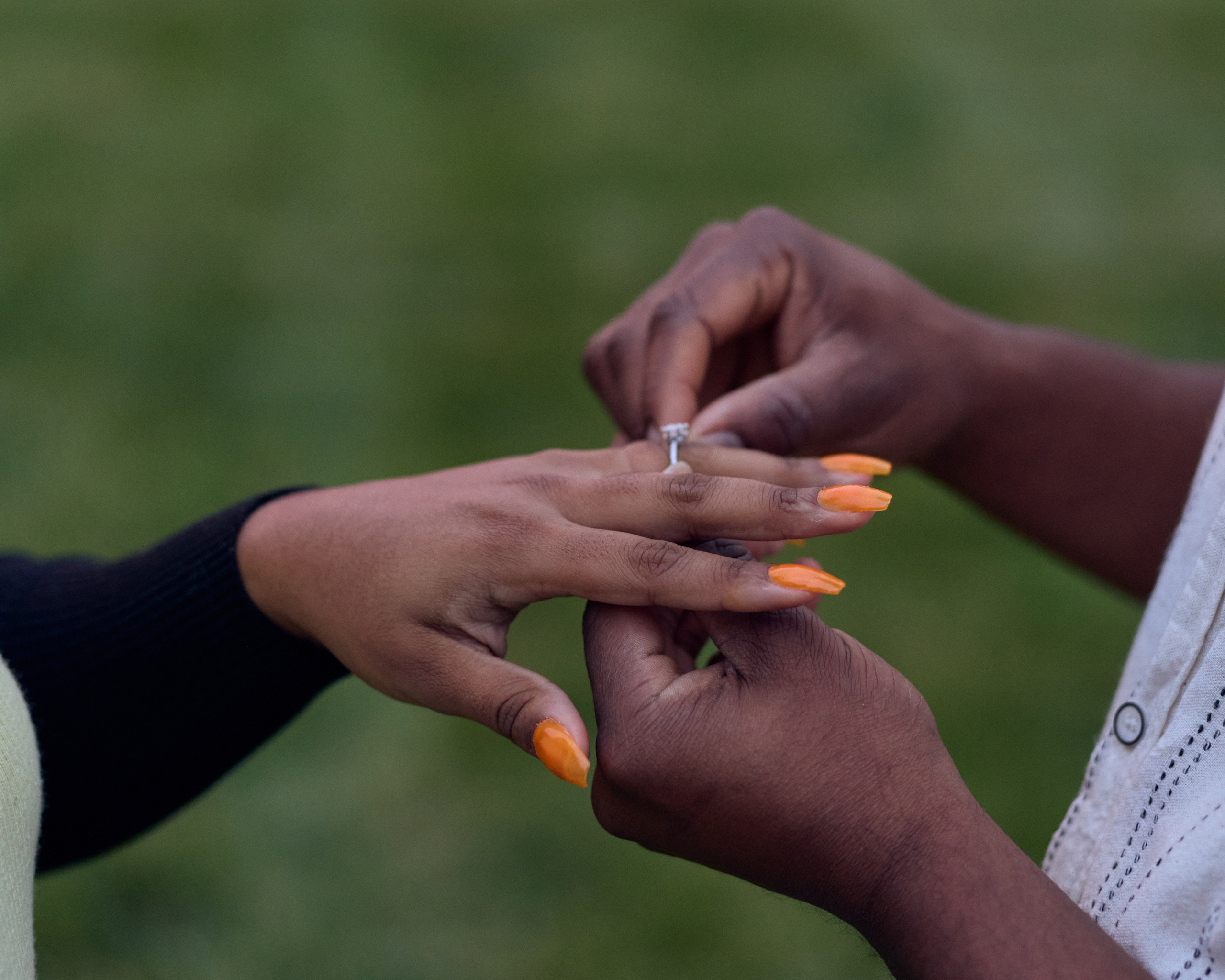  Close-up of an engagement ring being placed on her finger
