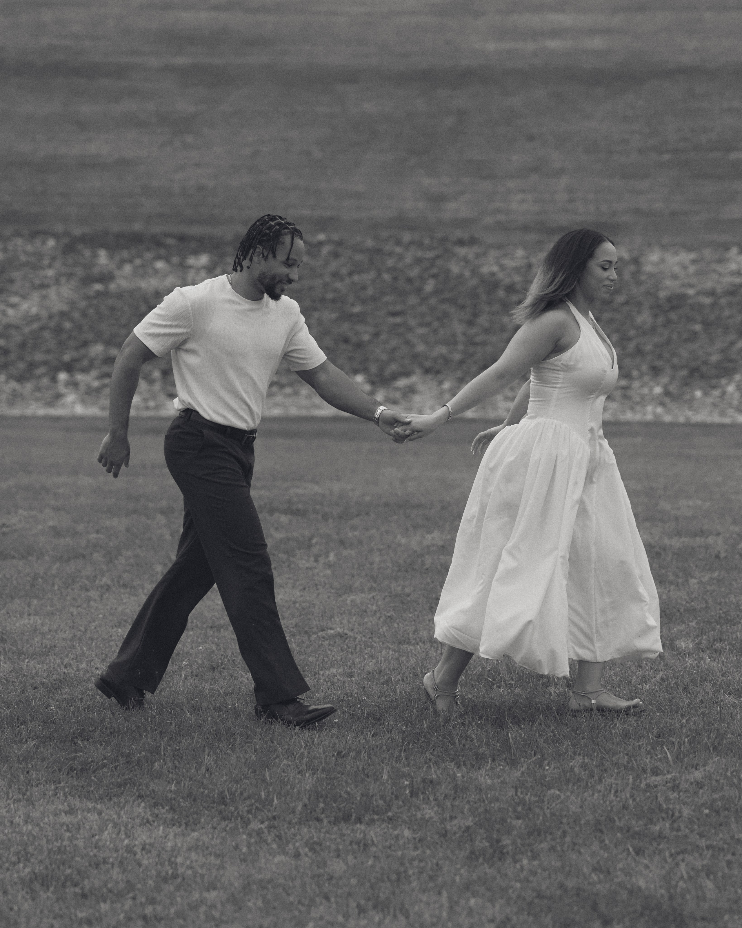 Black and white photo of a couple walking hand in hand through a meadow in Ohio
