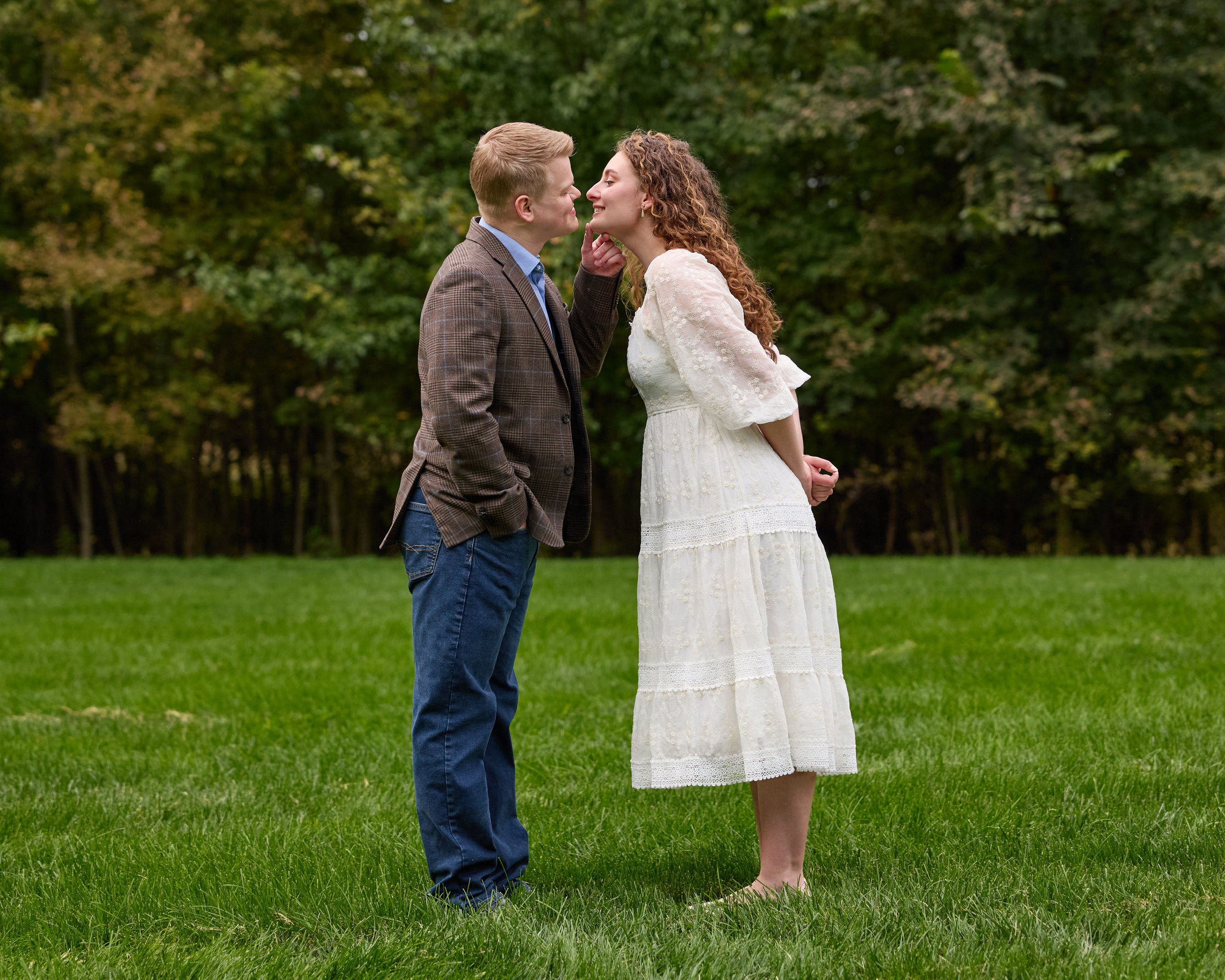 Laughing couple facing each other on a green lawn at Swan Lake Event Center