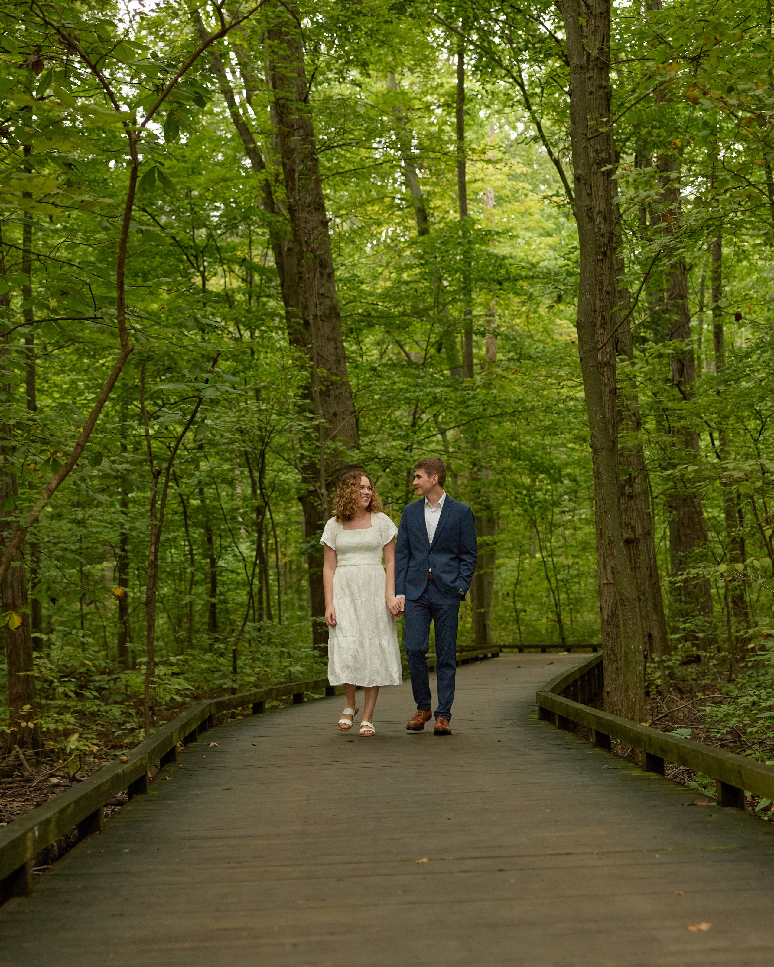 Couple walking a wooden boardwalk through the woods at Inniswood, Ohio