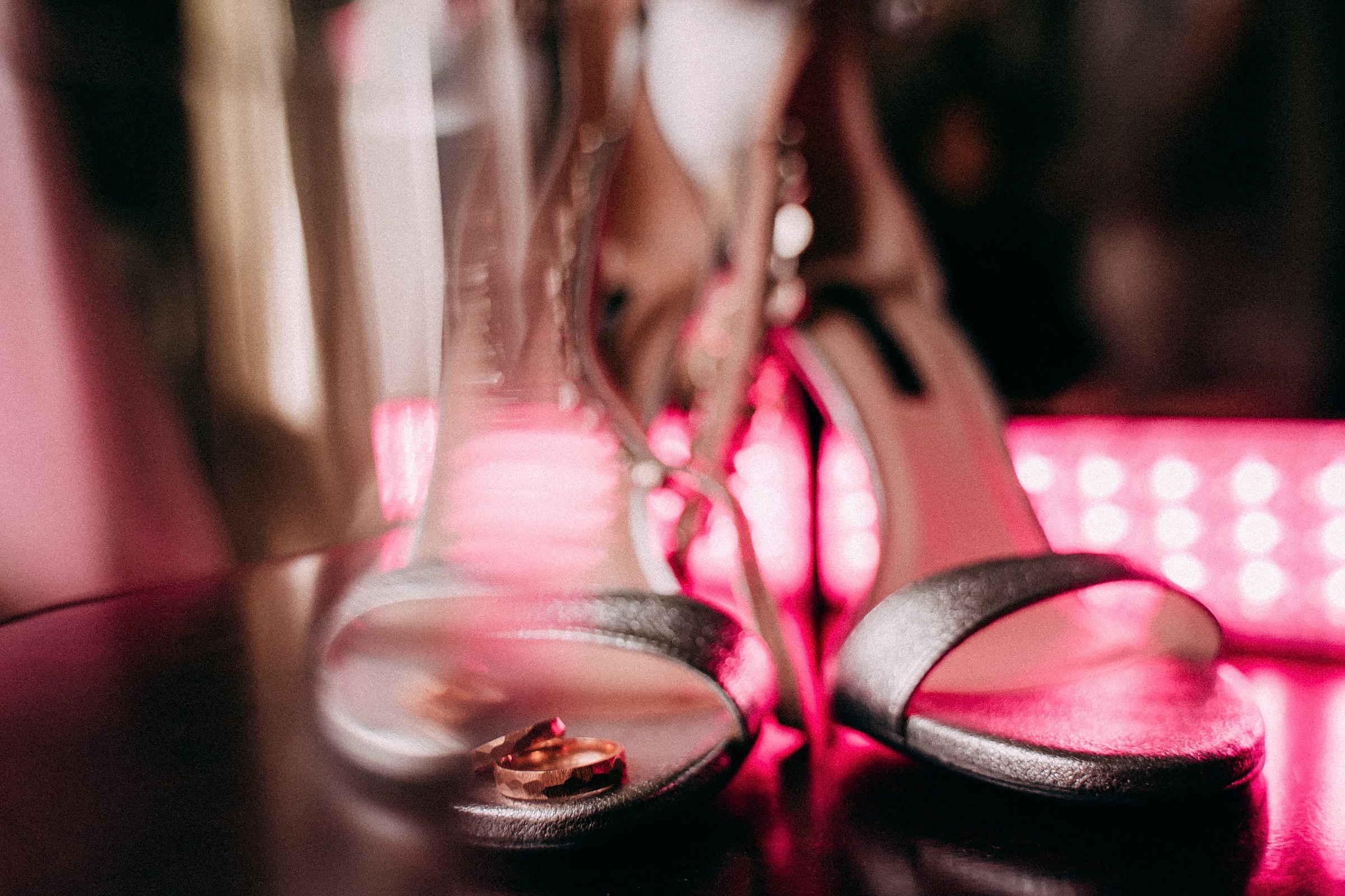 Silver heel sandals lighted up with a pink light on a background 