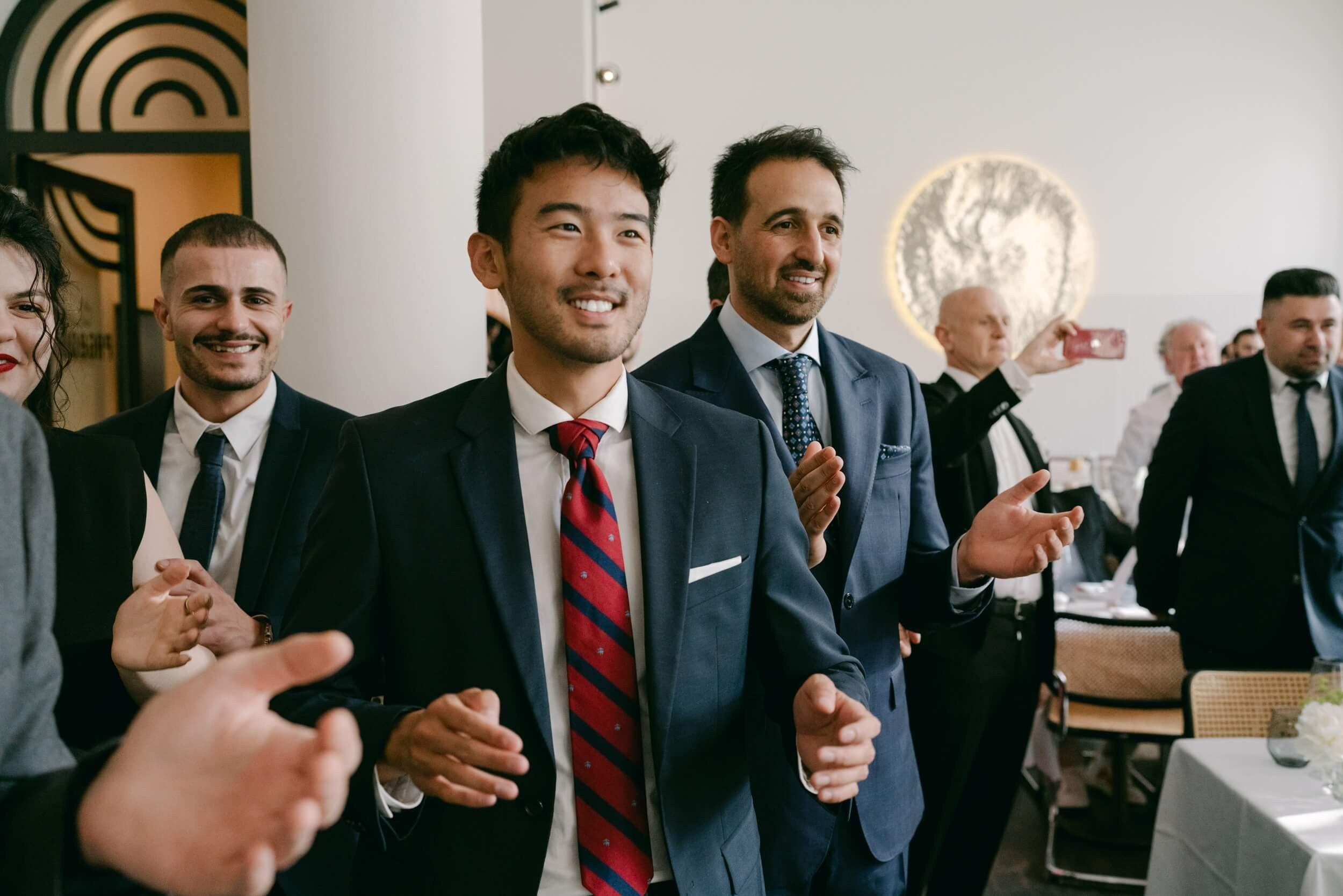 Fun group photo of the groom with male wedding guests in bold colourful outfits, lively reception moment at Bayerischer Hof Munich photographed by Inna Zaytseva