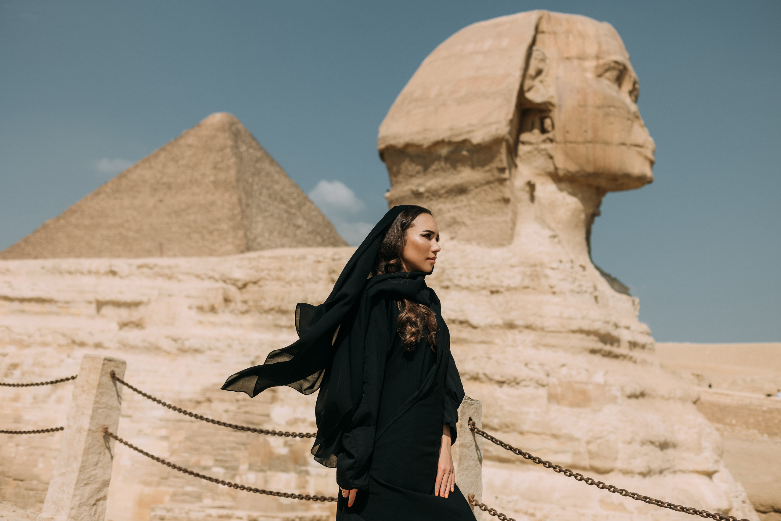 Девушка в абайе на фоне Сфинкса и пирамид