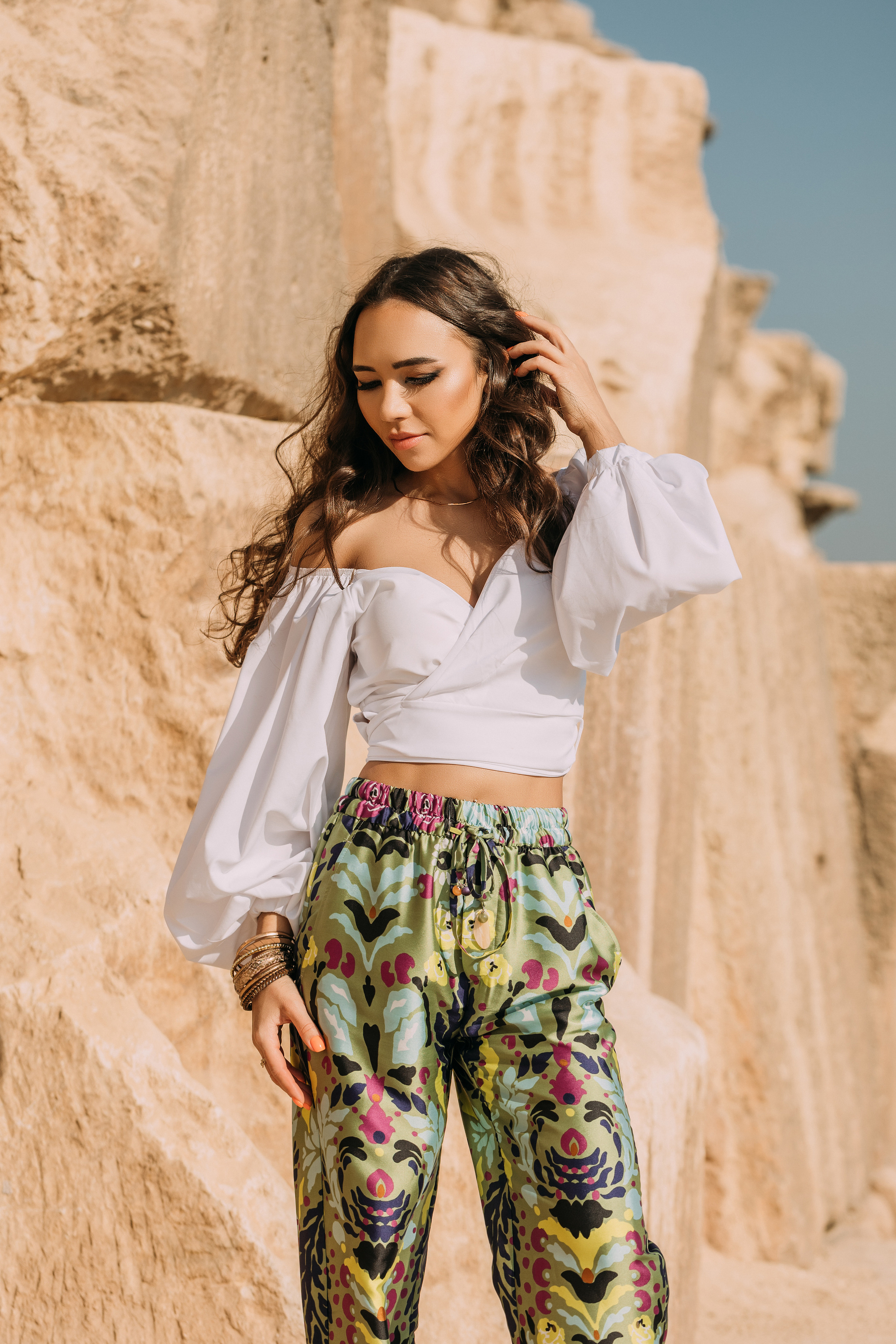 Девушка в белой блузке и цветастых брюках у пирамиды Хеопса