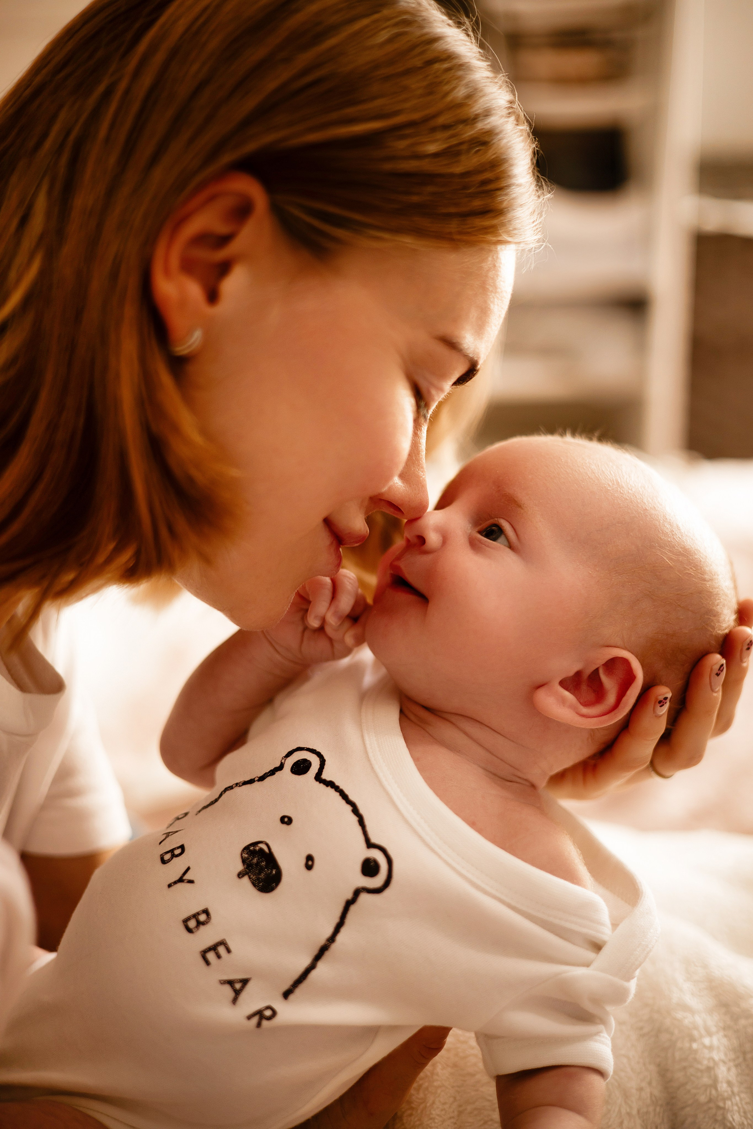 Mother and newborn smiling during a home photoshoot