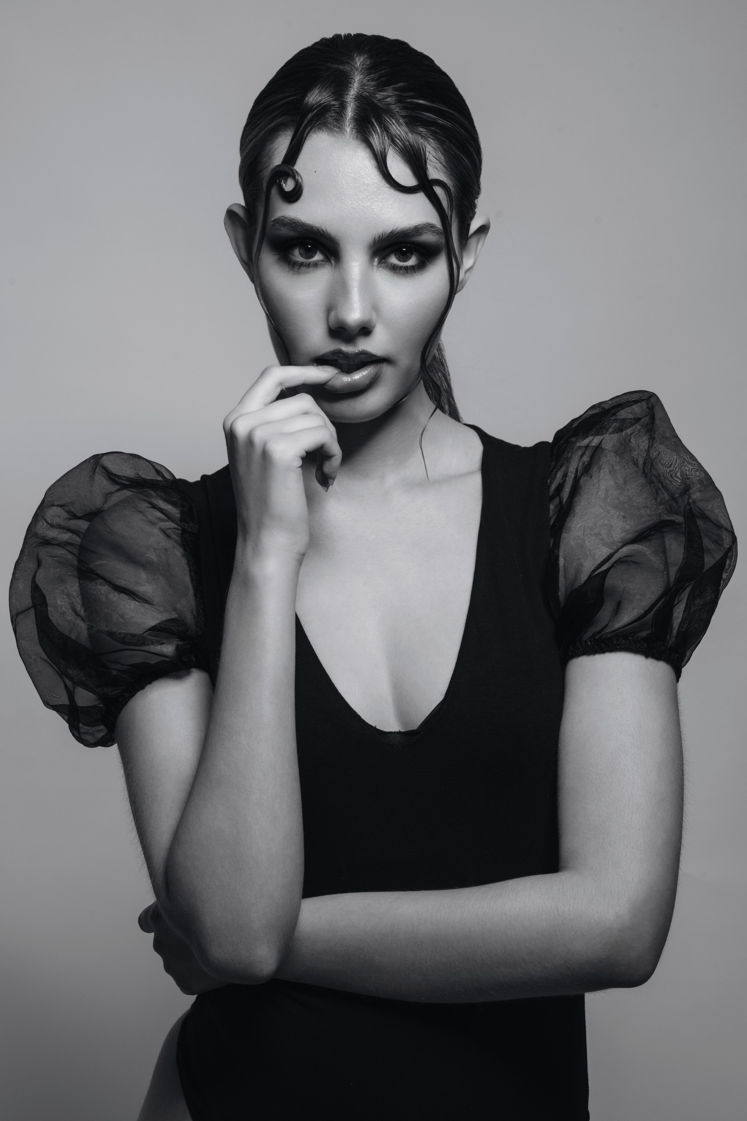 Black and white portrait of a woman in a dress with sheer sleeves, photographed in a refined editorial style with a strong fashion-led composition.
