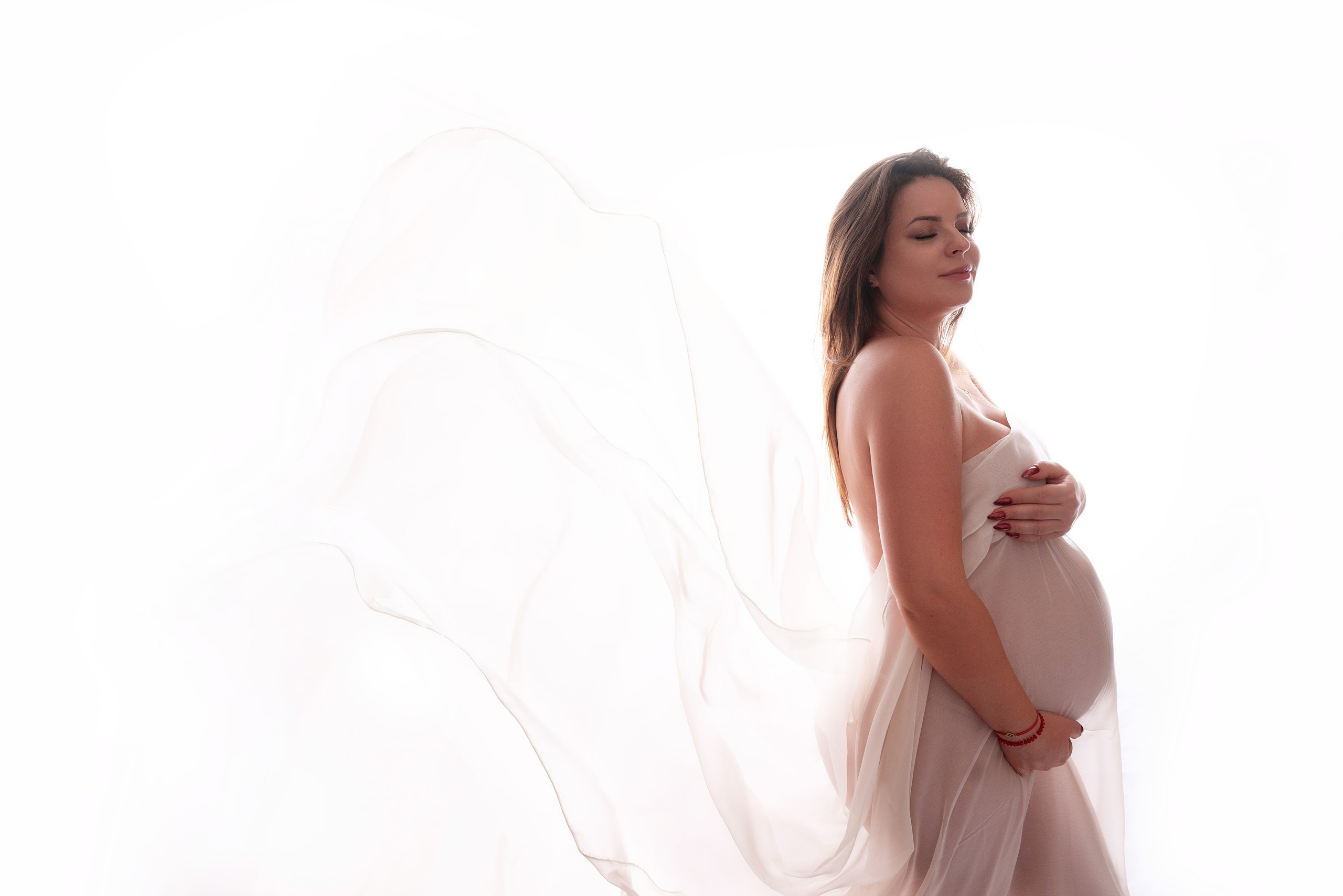 Zartes und sinnliches Schwangerschaftsfoto mit fliegendem Seidenstoff