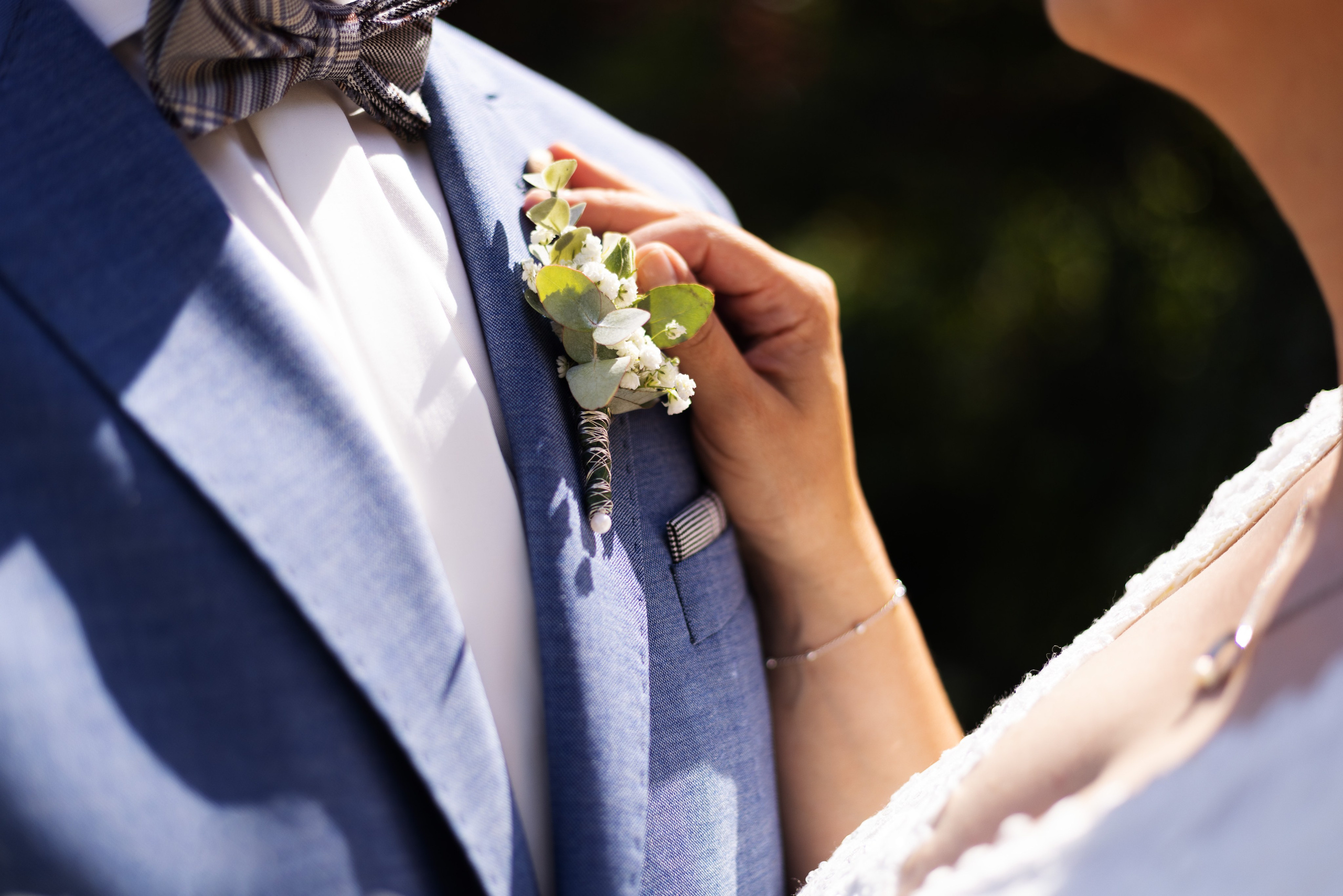 Hochzeitsfoto auf einem Feld bei Sonnenuntergang, Brautpaar lehnt an Strohballen in ländlicher Idylle