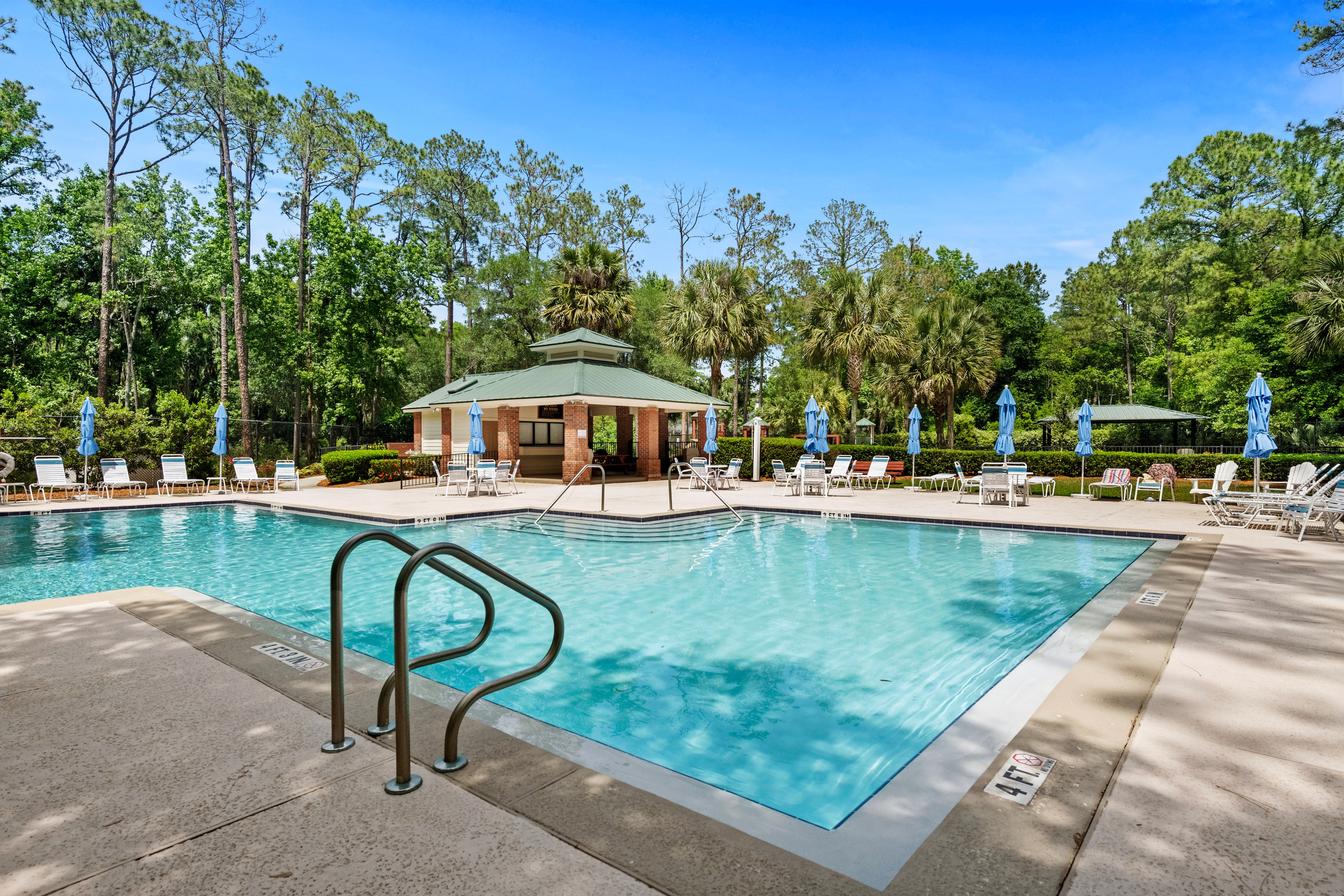 Resort-style pool with umbrellas and clubhouse