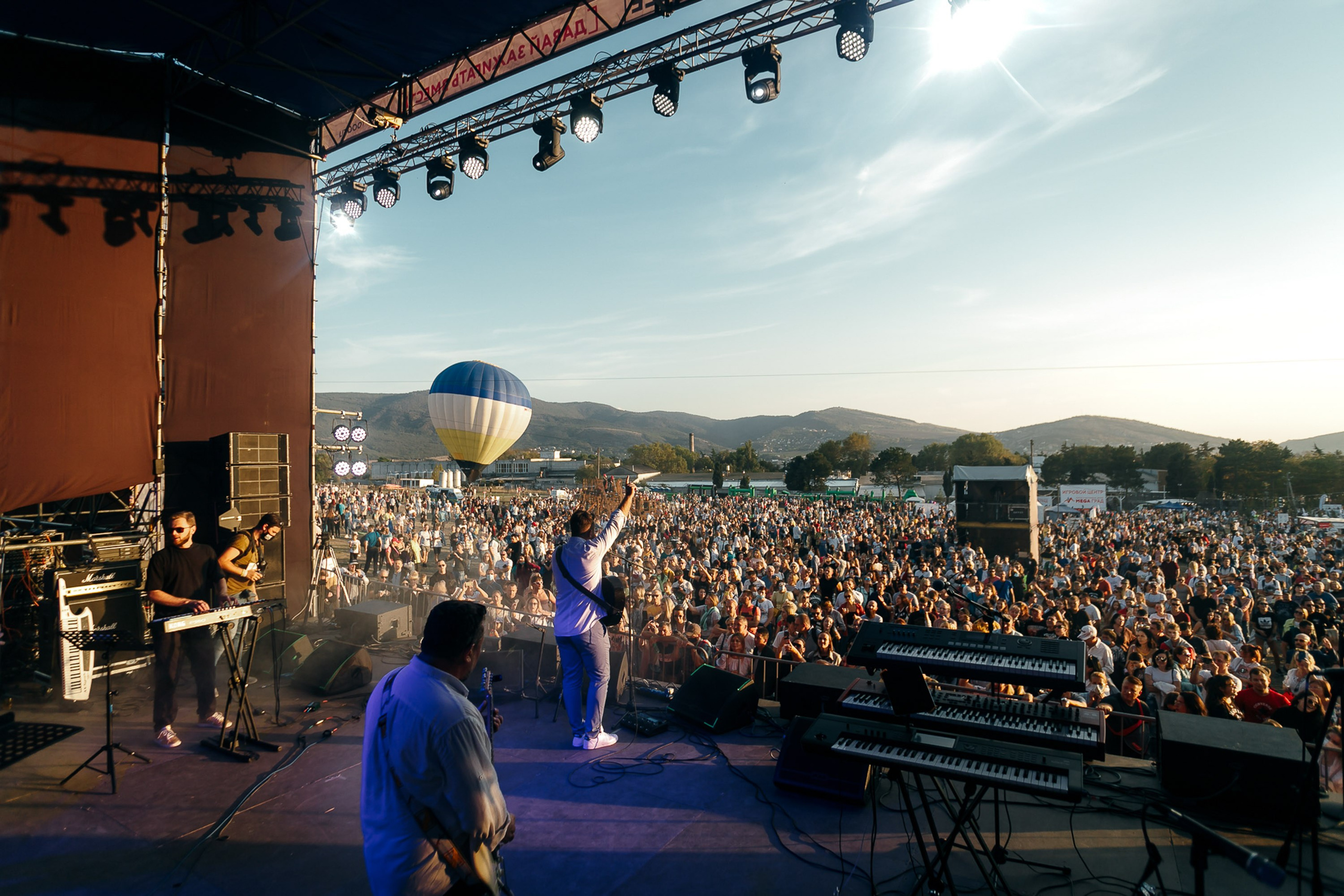 Outdoor stage with crowd and performer at sunset