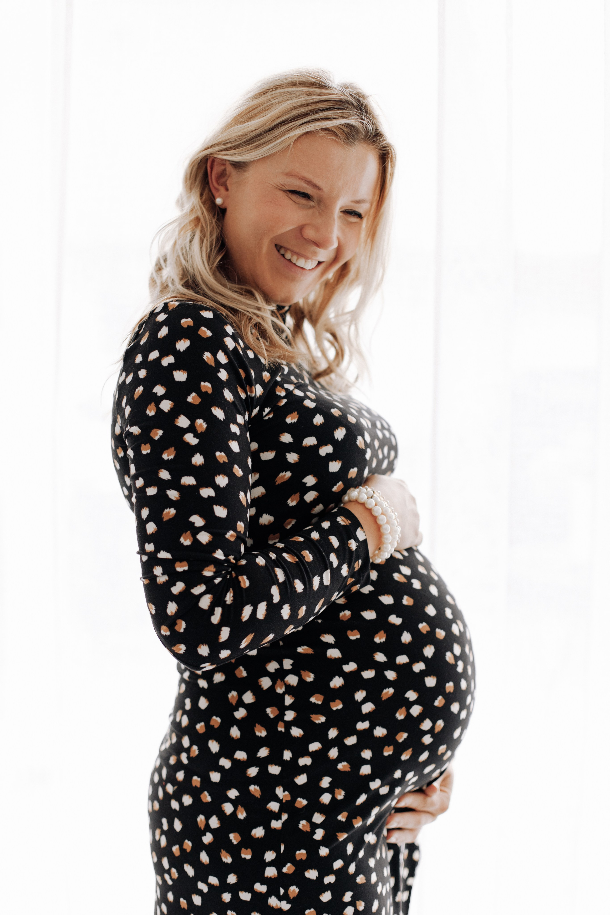 Frau hält ihren Babybauch und steht im Fotostudio in Aschaffenburg während eines Schwangerschaftsshootings